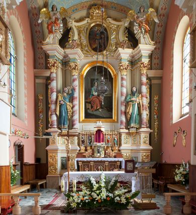 Zdjęcie nr 4: Nastawa ołtarzowa architektoniczna, jednoosiowa, jednokondygnacyjna ze zwieńczeniem, na podwójnym cokole. Ołtarz drewniany, prostopadłościenny; mensa drewniana z kamiennym portatylem. Antepedium podzielone na trzy pola czterema półkolumnami o stylizowanych kapitelach. W polach płyciny; w środkowej romb z płaskorzeźbionym kielichem z hostią; w zewnętrznych winne grona z kłosami zbóż.Tabernakulum w formie drewnianej skrzynki obitej blachą. Drzwiczki w kształcie stojącego prostokąta z aplikowaną, odlewaną plakietką ze sceną modlitwy Chrystusa w Ogrójcu, w narożach aplikowane uskrzydlone główki anielskie, całość w opasce dekorowanej różami. Tabernakulum w drewnianej obudowie, ściana frontowa flankowana parą kolumn. Tron wystawienia w formie niszy ujętej kolumienkami z łukiem o fantazyjnym wykroju. Całość zwieńczona rzeźbioną figurką Baranka Eucharystycznego leżącego na księdze. Po bokach tabernakulum stoją dwie pary nisz na postumentach z figurami czterech ewangelistów. Kondygnacja nastawy ujęta dwiema parami kolumn o kapitelach kompozytowych, stojących na tle zwielokrotnionych pilastrów. Podpory dźwigają fragmenty wyłamanego belkowania, zewnętrzna para również przerwany, wklęsło-wypukły przyczółek. Cokoły ustawione delikatnie pod kątem, zwrócone na zewnątrz. Na gzymsie wewnętrznych podpór niewielkie figurki puttów; na przyczółkach figury siedzących aniołów ubranych w długie suknie, okryte czerwonymi płaszczami. Między kolumnami na wspornikach figury św. Piotra i św. Pawła. W polu środkowym obraz św. Aleksego w profilowanej ramie w kształcie stojącego prostokąta zamkniętego łukiem półkolistym nadwieszonym. Zwieńczenie w formie leżącego prostokąta, ujętego masywnymi spływami wolutowymi, zamkniętego przeciwstawnie zwróconymi esownicami. W polu obraz św. Michała Archanioła w profilowanej ramie w formie stojącego owalu. Dolne partie cokołu dekorowane płaskorzeźbionym, stylizowanym akantem o układzie geometrycznym; wyższe z ornamentem w płycinach. Kondygnacja ujęta uszakami utworzonymi z karbowanej wstęgi przeplatającej się z ornamentem roślinnym. Woluty zwieńczenia dekorowane liśćmi palmowymi i kampanullami. Obraz w polu ujęty muszlami i liśćmi palmowymi; całość zwieńczona muszlą. Struktura polichromowana w odcieniu bieli; płyciny i fryz polichromowane na seledynowo, profile w odcieniu jasnego różu; trzony kolumn marmoryzowane; ornamentyka, kapitele, profile i ornamenty złocone i srebrzone.