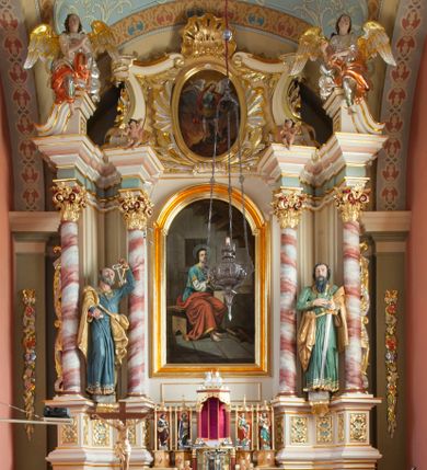 Zdjęcie nr 1: Nastawa ołtarzowa architektoniczna, jednoosiowa, jednokondygnacyjna ze zwieńczeniem, na podwójnym cokole. Ołtarz drewniany, prostopadłościenny; mensa drewniana z kamiennym portatylem. Antepedium podzielone na trzy pola czterema półkolumnami o stylizowanych kapitelach. W polach płyciny; w środkowej romb z płaskorzeźbionym kielichem z hostią; w zewnętrznych winne grona z kłosami zbóż.Tabernakulum w formie drewnianej skrzynki obitej blachą. Drzwiczki w kształcie stojącego prostokąta z aplikowaną, odlewaną plakietką ze sceną modlitwy Chrystusa w Ogrójcu, w narożach aplikowane uskrzydlone główki anielskie, całość w opasce dekorowanej różami. Tabernakulum w drewnianej obudowie, ściana frontowa flankowana parą kolumn. Tron wystawienia w formie niszy ujętej kolumienkami z łukiem o fantazyjnym wykroju. Całość zwieńczona rzeźbioną figurką Baranka Eucharystycznego leżącego na księdze. Po bokach tabernakulum stoją dwie pary nisz na postumentach z figurami czterech ewangelistów. Kondygnacja nastawy ujęta dwiema parami kolumn o kapitelach kompozytowych, stojących na tle zwielokrotnionych pilastrów. Podpory dźwigają fragmenty wyłamanego belkowania, zewnętrzna para również przerwany, wklęsło-wypukły przyczółek. Cokoły ustawione delikatnie pod kątem, zwrócone na zewnątrz. Na gzymsie wewnętrznych podpór niewielkie figurki puttów; na przyczółkach figury siedzących aniołów ubranych w długie suknie, okryte czerwonymi płaszczami. Między kolumnami na wspornikach figury św. Piotra i św. Pawła. W polu środkowym obraz św. Aleksego w profilowanej ramie w kształcie stojącego prostokąta zamkniętego łukiem półkolistym nadwieszonym. Zwieńczenie w formie leżącego prostokąta, ujętego masywnymi spływami wolutowymi, zamkniętego przeciwstawnie zwróconymi esownicami. W polu obraz św. Michała Archanioła w profilowanej ramie w formie stojącego owalu. Dolne partie cokołu dekorowane płaskorzeźbionym, stylizowanym akantem o układzie geometrycznym; wyższe z ornamentem w płycinach. Kondygnacja ujęta uszakami utworzonymi z karbowanej wstęgi przeplatającej się z ornamentem roślinnym. Woluty zwieńczenia dekorowane liśćmi palmowymi i kampanullami. Obraz w polu ujęty muszlami i liśćmi palmowymi; całość zwieńczona muszlą. Struktura polichromowana w odcieniu bieli; płyciny i fryz polichromowane na seledynowo, profile w odcieniu jasnego różu; trzony kolumn marmoryzowane; ornamentyka, kapitele, profile i ornamenty złocone i srebrzone.