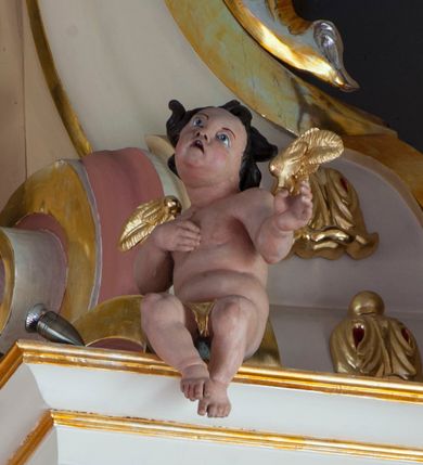 Zdjęcie nr 19: Nastawa ołtarzowa architektoniczna, jednoosiowa, jednokondygnacyjna ze zwieńczeniem, na podwójnym cokole. Ołtarz drewniany, prostopadłościenny; mensa drewniana z kamiennym portatylem. Antepedium podzielone na trzy pola czterema półkolumnami o stylizowanych kapitelach. W polach płyciny; w środkowej romb z płaskorzeźbionym kielichem z hostią; w zewnętrznych winne grona z kłosami zbóż.Tabernakulum w formie drewnianej skrzynki obitej blachą. Drzwiczki w kształcie stojącego prostokąta z aplikowaną, odlewaną plakietką ze sceną modlitwy Chrystusa w Ogrójcu, w narożach aplikowane uskrzydlone główki anielskie, całość w opasce dekorowanej różami. Tabernakulum w drewnianej obudowie, ściana frontowa flankowana parą kolumn. Tron wystawienia w formie niszy ujętej kolumienkami z łukiem o fantazyjnym wykroju. Całość zwieńczona rzeźbioną figurką Baranka Eucharystycznego leżącego na księdze. Po bokach tabernakulum stoją dwie pary nisz na postumentach z figurami czterech ewangelistów. Kondygnacja nastawy ujęta dwiema parami kolumn o kapitelach kompozytowych, stojących na tle zwielokrotnionych pilastrów. Podpory dźwigają fragmenty wyłamanego belkowania, zewnętrzna para również przerwany, wklęsło-wypukły przyczółek. Cokoły ustawione delikatnie pod kątem, zwrócone na zewnątrz. Na gzymsie wewnętrznych podpór niewielkie figurki puttów; na przyczółkach figury siedzących aniołów ubranych w długie suknie, okryte czerwonymi płaszczami. Między kolumnami na wspornikach figury św. Piotra i św. Pawła. W polu środkowym obraz św. Aleksego w profilowanej ramie w kształcie stojącego prostokąta zamkniętego łukiem półkolistym nadwieszonym. Zwieńczenie w formie leżącego prostokąta, ujętego masywnymi spływami wolutowymi, zamkniętego przeciwstawnie zwróconymi esownicami. W polu obraz św. Michała Archanioła w profilowanej ramie w formie stojącego owalu. Dolne partie cokołu dekorowane płaskorzeźbionym, stylizowanym akantem o układzie geometrycznym; wyższe z ornamentem w płycinach. Kondygnacja ujęta uszakami utworzonymi z karbowanej wstęgi przeplatającej się z ornamentem roślinnym. Woluty zwieńczenia dekorowane liśćmi palmowymi i kampanullami. Obraz w polu ujęty muszlami i liśćmi palmowymi; całość zwieńczona muszlą. Struktura polichromowana w odcieniu bieli; płyciny i fryz polichromowane na seledynowo, profile w odcieniu jasnego różu; trzony kolumn marmoryzowane; ornamentyka, kapitele, profile i ornamenty złocone i srebrzone.