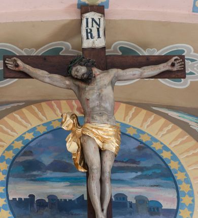 Zdjęcie nr 1: Martwe ciało Zbawiciela o wyraźnie zaznaczonej muskulaturze jest rozciągnięte i przybite trzema gwoździami do prostego krzyża. Widać na nim ślady męki: strużki krwi płynące po ciele, przebity bok oraz krwawiące rany. Głowa jest opuszczona całkowicie na prawe ramię, oczy zamknięte, usta nieznacznie rozchylone; na głowie ciemnozielona korona cierniowa. Chrystus ma rozpostarte ręce, stopy założone na siebie, prawa na lewej, przybite jednym gwoździem. Biodra otacza złote perizonium przewiązane na prawym boku, z końcami rozwiewającymi się w górę i w dół. Na górnym ramieniu krzyża widnieje rozwinięty titulus z majuskułowymi literami „IN/RI” (łac. Iesus Nazarenus Rex Iudaeorum).