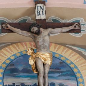 Zdjęcie nr 1: Martwe ciało Zbawiciela o wyraźnie zaznaczonej muskulaturze jest rozciągnięte i przybite trzema gwoździami do prostego krzyża. Widać na nim ślady męki: strużki krwi płynące po ciele, przebity bok oraz krwawiące rany. Głowa jest opuszczona całkowicie na prawe ramię, oczy zamknięte, usta nieznacznie rozchylone; na głowie ciemnozielona korona cierniowa. Chrystus ma rozpostarte ręce, stopy założone na siebie, prawa na lewej, przybite jednym gwoździem. Biodra otacza złote perizonium przewiązane na prawym boku, z końcami rozwiewającymi się w górę i w dół. Na górnym ramieniu krzyża widnieje rozwinięty titulus z majuskułowymi literami „IN/RI” (łac. Iesus Nazarenus Rex Iudaeorum).