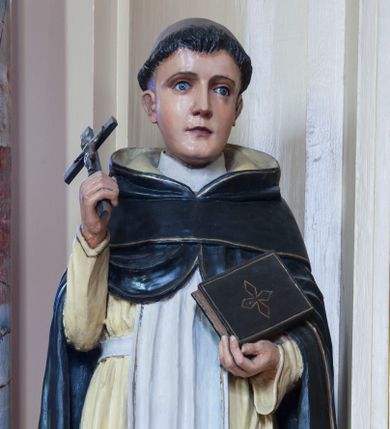 Zdjęcie nr 1: Rzeźba drążona z tyłu przedstawiająca stojącą na niewysokim, prostopadłościennym cokole postać św. Dominika. Święty jest ustawiony frontalnie. Twarz ma owalną, o delikatnych, młodzieńczych rysach, z jasnymi oczami, wąskim nosem i niewielkimi ustami; na głowie wycięta tonsura. Jest ubrany w strój dominikański: biały habit ze szkaplerzem i czarny płaszcz z kapturem. W prawej dłoni trzyma krucyfiks, w lewej zamkniętą księgę. Polichromia w partiach ciała naturalistyczna.