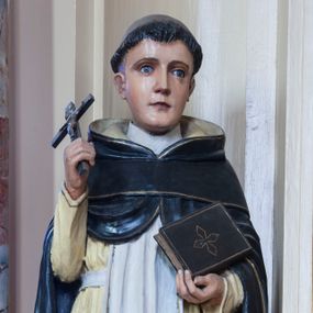 Zdjęcie nr 1: Rzeźba drążona z tyłu przedstawiająca stojącą na niewysokim, prostopadłościennym cokole postać św. Dominika. Święty jest ustawiony frontalnie. Twarz ma owalną, o delikatnych, młodzieńczych rysach, z jasnymi oczami, wąskim nosem i niewielkimi ustami; na głowie wycięta tonsura. Jest ubrany w strój dominikański: biały habit ze szkaplerzem i czarny płaszcz z kapturem. W prawej dłoni trzyma krucyfiks, w lewej zamkniętą księgę. Polichromia w partiach ciała naturalistyczna.