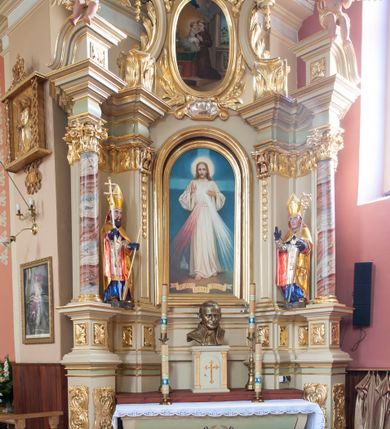 Zdjęcie nr 2: Nastawa ołtarzowa architektoniczna, jednoosiowa, jednokondygnacyjna ze zwieńczeniem, na potrójnym cokole. Ołtarz drewniany, prostopadłościenny; mensa drewniana z kamiennym portatylem. Antepedium zdobione polichromowanym monogramem IHS ujętym dekoracją roślinną. Tabernakulum prostopadłościenne, na cokole, zwieńczone gzymsem. Na ściance frontowej flankowanej pilastrami, drzwiczki w kształcie stojącego prostokąta zamkniętego łukiem półkolistym, dekorowane krzyżem o ramionach zakończonych trójlistnie. Kondygnacja nastawy ujęta parą pilastrów i kolumn o kapitelach kompozytowych, stojących na tle zwielokrotnionych pilastrów. Podpory dźwigają fragmenty wyłamanego belkowania, zewnętrzna para również przerwany, wklęsło-wypukły przyczółek. Cokoły ustawione delikatnie pod kątem, zwrócone na zewnątrz. Na gzymsie zewnętrznych podpór niewielkie figurki puttów. Między kolumnami a pilastrami, na wspornikach figury św. Stanisława i św. Wojciecha. W polu środkowym obraz „Jezu Ufam Tobie” w profilowanej ramie w kształcie stojącego prostokąta zamkniętego łukiem półkolistym. Zwieńczenie w formie stojącego prostokąta o wklęsłych bokach, ujętego spływami wolutowymi. W polu obraz św. Antoniego w profilowanej ramie w kształcie stojącego owalu. Dolne partie cokołu dekorowane płaskorzeźbionym, stylizowanym akantem o układzie geometrycznym; wyższy z ornamentem w płycinach. Na ściankach filarów kampanule, woluty zwieńczenia dekorowane liśćmi palmowymi i kampanulami. Obraz w polu ujęty liśćmi palmowymi i karbowaną wstążką, od dołu i góry muszlami. Struktura polichromowana w odcieniu bieli; płyciny i fryz polichromowane na seledynowo, profile w odcieniu beżowym; trzony kolumn marmoryzowane; ornamentyka, kapitele, profile i ornamenty złocone i srebrzone. 