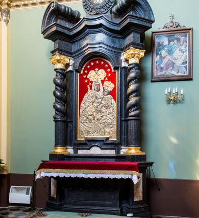 Zdjęcie nr 2: Ołtarz prostopadłościenny, w typie tumbowym, z mensą o brzegu zdobionym rzędem liści akantu naprzemian z łukami kotarowymi zwieńczonymi kulami oraz podwieszonym lambrekinem. Nastawa ołtarzowa jest architektoniczna, jednoosiowa ze zwieńczeniem, ujęta przez kolumny stojące na ukośnie dostawionych cokołach. Kolumny w jednej trzeciej kanelowane w dwóch trzecich skręcone z wplecioną wicią roślinną, ze złoconym kapitelem podtrzymują przerwany przyczółek ze ślimacznicami. Belkowanie bogato profilowane nad częścią środkową jest wyłamane trzema wklęsłymi łukami. W szczycie owalny medalion z monogramem ”MARIA”, w obramieniu z wieńca laurowego, ślimacznic i festonów, zakończony krzyżem. W osi środkowej prostokątna wnęka w profilowanym obramieniu, zamknięta półkolistym łukiem nadwieszonym z obrazem Matki Boskiej z Dzieciątkiem. 