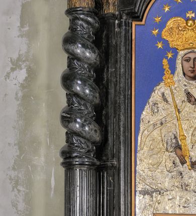 Zdjęcie nr 9: Ołtarz prostopadłościenny, w typie tumbowym, z mensą o brzegu zdobionym rzędem liści akantu naprzemian z łukami kotarowymi zwieńczonymi kulami oraz podwieszonym lambrekinem. Nastawa ołtarzowa jest architektoniczna, jednoosiowa ze zwieńczeniem, ujęta przez kolumny stojące na ukośnie dostawionych cokołach. Kolumny w jednej trzeciej kanelowane w dwóch trzecich skręcone z wplecioną wicią roślinną, ze złoconym kapitelem podtrzymują przerwany przyczółek ze ślimacznicami. Belkowanie bogato profilowane nad częścią środkową jest wyłamane trzema wklęsłymi łukami. W szczycie owalny medalion z monogramem ”MARIA”, w obramieniu z wieńca laurowego, ślimacznic i festonów, zakończony krzyżem. W osi środkowej prostokątna wnęka w profilowanym obramieniu, zamknięta półkolistym łukiem nadwieszonym z obrazem Matki Boskiej z Dzieciątkiem. 