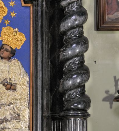 Zdjęcie nr 7: Ołtarz prostopadłościenny, w typie tumbowym, z mensą o brzegu zdobionym rzędem liści akantu naprzemian z łukami kotarowymi zwieńczonymi kulami oraz podwieszonym lambrekinem. Nastawa ołtarzowa jest architektoniczna, jednoosiowa ze zwieńczeniem, ujęta przez kolumny stojące na ukośnie dostawionych cokołach. Kolumny w jednej trzeciej kanelowane w dwóch trzecich skręcone z wplecioną wicią roślinną, ze złoconym kapitelem podtrzymują przerwany przyczółek ze ślimacznicami. Belkowanie bogato profilowane nad częścią środkową jest wyłamane trzema wklęsłymi łukami. W szczycie owalny medalion z monogramem ”MARIA”, w obramieniu z wieńca laurowego, ślimacznic i festonów, zakończony krzyżem. W osi środkowej prostokątna wnęka w profilowanym obramieniu, zamknięta półkolistym łukiem nadwieszonym z obrazem Matki Boskiej z Dzieciątkiem. 