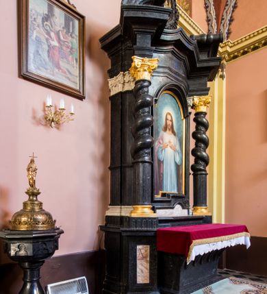 Zdjęcie nr 2: Ołtarz prostopadłościenny, w typie tumbowym, z mensą o brzegu zdobionym rzędem liści akantu naprzemian z łukami kotarowymi zwieńczonymi kulami oraz podwieszonym lambrekinem. Nastawa ołtarzowa jest architektoniczna, jednoosiowa ze zwieńczeniem, ujęta przez kolumny stojące na ukośnie dostawionych cokołach. Kolumny w jednej trzeciej kanelowane w dwóch trzecich skręcone z wplecioną wicią roślinną, ze złoconym kapitelem podtrzymują przerwany przyczółek ze ślimacznicami. Belkowanie bogato profilowane nad częścią środkową jest wyłamane trzema wklęsłymi łukami. W szczycie owalny medalion z monogramem &quot;IHS”, w obramieniu z wieńca laurowego, ślimacznim z festonami, zakończony krzyżem. W osi środkowej prostokątna wnęka w profilowanym obramieniu, zamknięta półkolistym łukiem nadwieszonym z obrazem Najświętszego Serca Jezusowego. 


