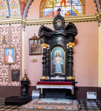 Zdjęcie nr 4: Ołtarz prostopadłościenny, w typie tumbowym, z mensą o brzegu zdobionym rzędem liści akantu naprzemian z łukami kotarowymi zwieńczonymi kulami oraz podwieszonym lambrekinem. Nastawa ołtarzowa jest architektoniczna, jednoosiowa ze zwieńczeniem, ujęta przez kolumny stojące na ukośnie dostawionych cokołach. Kolumny w jednej trzeciej kanelowane w dwóch trzecich skręcone z wplecioną wicią roślinną, ze złoconym kapitelem podtrzymują przerwany przyczółek ze ślimacznicami. Belkowanie bogato profilowane nad częścią środkową jest wyłamane trzema wklęsłymi łukami. W szczycie owalny medalion z monogramem &quot;IHS”, w obramieniu z wieńca laurowego, ślimacznim z festonami, zakończony krzyżem. W osi środkowej prostokątna wnęka w profilowanym obramieniu, zamknięta półkolistym łukiem nadwieszonym z obrazem Najświętszego Serca Jezusowego. 


