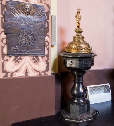 Zdjęcie nr 1: Podstawa na rzucie ośmioboku, dwuczęściowa, dolna część szeroka i niska o fazowanych krawędziach, górna wysoka i wąska. Trzon gładki, gruszkowaty, ujęty dwoma pierścieniami. Czara w dolnej części półkulista i gładka, w górnej ośmioboczna, zdobiona wgłębnymi ślepymi maswerkami, zakończona wydatnym, profilowanym gzymsem. Pokrywa metalowa, pozłacana. Brzeg w formie korony, zdobiony maswerkami oraz koronką w formie przestylizowanych lilii. Czasza półkulista zdobiona łuskami, zwieńczona cylindrycznym postumentem z dolną częścią zdobioną maswerkami, środkową w kształcie gładkiej wklęski i i górną, profilowaną z niewielką koronką. Na nim, na ośmiobocznym cokoliku, pełnoplastyczna postać św. Jana Chrzciciela z krzyżem w lewej ręce i barankiem leżącym na księdze w prawej. Jego twarz jest pociągła, święty spogląda w dół, ma długie włosy, opadające na plecy i ramiona. Jest ubrany w wielbłądzią skórę i płaszcz zarzucony na prawym ramieniu. 