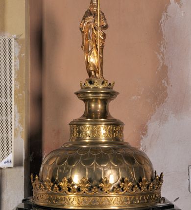 Zdjęcie nr 4: Podstawa na rzucie ośmioboku, dwuczęściowa, dolna część szeroka i niska o fazowanych krawędziach, górna wysoka i wąska. Trzon gładki, gruszkowaty, ujęty dwoma pierścieniami. Czara w dolnej części półkulista i gładka, w górnej ośmioboczna, zdobiona wgłębnymi ślepymi maswerkami, zakończona wydatnym, profilowanym gzymsem. Pokrywa metalowa, pozłacana. Brzeg w formie korony, zdobiony maswerkami oraz koronką w formie przestylizowanych lilii. Czasza półkulista zdobiona łuskami, zwieńczona cylindrycznym postumentem z dolną częścią zdobioną maswerkami, środkową w kształcie gładkiej wklęski i i górną, profilowaną z niewielką koronką. Na nim, na ośmiobocznym cokoliku, pełnoplastyczna postać św. Jana Chrzciciela z krzyżem w lewej ręce i barankiem leżącym na księdze w prawej. Jego twarz jest pociągła, święty spogląda w dół, ma długie włosy, opadające na plecy i ramiona. Jest ubrany w wielbłądzią skórę i płaszcz zarzucony na prawym ramieniu. 