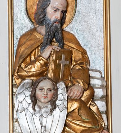 Zdjęcie nr 12: Ambona przyścienna, wisząca, z dostępem od lewej strony w postaci jednobiegowych schodów z balustradą. Kosz na planie sześcioboku na profilowanym cokole i ćwierćwałku; u spodu podwieszony profilowany ostrosłup o ściętym szczycie, zakończony szyszką. Ścianki kosza wydzielone kolumienkami  o trzonach dekorowanych do 1/3 wysokości kanelowaniem, o kapitelach korynckich, na cokołach zdobionych liśćmi akantu, dźwigającymi imposty oraz wspólny gzyms stanowiąc parapet. W polach ścianek płyciny z płaskorzeźbionymi półpostaciami czterech ewangelistów, każdy z nich ukazany został z złotej sukni, z identyfikującym go atrybutem, księgą lub zwojem i piórem w ręce –  od lewej św. Jan, św. Mateusz, św. Łukasz i św. Marek. Zaplecek w formie wydłużonego prostokąta, ujętego pilastrami podtrzymującymi imposty i wspólny gzyms. W polu płycina w formie stojącego prostokąta zamkniętego łukiem półkolistym z płaskorzeźbionym przedstawieniem Chrystusa Dobrego Pasterza, u spodu płycina z napisem „KTO WAS SŁUCHA / MNIE SŁUCHA”.  Chrystus został ukazany w całej postaci, lewą ręką podtrzymując baranka, a prawą laskę pasterską. Ma podłużna, poważną twarz, małe, niebieskie oczy, wąski nos i usta, broda dzieli się w dwa pukle; falowane włosy opadają na ramiona. Jest ubrany w długą, złotą tunikę i złoty płaszcz, na głowie ma złoty kalepusz, czerwony od wewnątrz. Stoi na trawie, u jego stóp dwa srebrzone baranki Zaplecek ujęty uszami w formie falujących liści. Baldachim powtarza kształt kosza, nakryty kopułką pokrytą łuską, z podwieszonym fryzem roślinnym, dekorowany w narożach palmetami. Baldachim stanowi podstawę dla latarni opartej na sześciu spływach wolutowych dekorowanych kampanulami, podtrzymujących belkowanie i kopułkę, stanowiącą cokół dla figury św. Jana Chrzciciela, który stoi w kontrapoście, prawą ręką unosi na wysokość twarzy muszlę, a e lewej trzyma trzyż. Ma podł€żną twarz okoczoną gęstym zarostem, wzniesiony ku górze wzrok, wąski nos i małe usta. Jest ubrany w tunikę ze srerzonego fuyta i złoty płaszcz wywiniety na prawym biodrze i przechodzący przez lewy bark. Wewnątrz latarni figura anioła na postumencie. Został ukazany w całej postaci, z rękami złożonymi na piersi. Ma okrągłą twarz o deliatnych rysach i falowane włosy opadające na kark. Jest ubrany w długa, złotą suknię w szerokomi rękawami. Z pleców wyrastają mu duże, srebrne skrzydła z ptacich piór. Na podniebiu baldachimu gołębica Ducha Świętego w glorii promienistej. Struktura polichromowana na biało, profile na czerwono, detale i ornamentyka złocone.