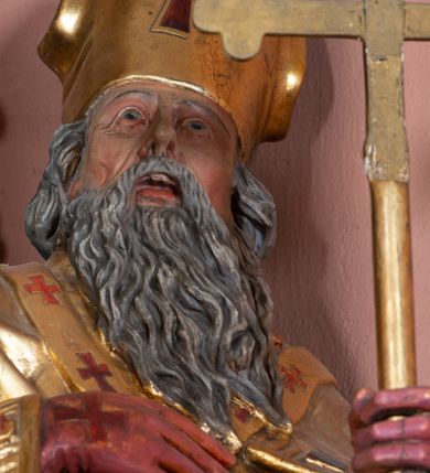 Zdjęcie nr 21: Nastawa ołtarzowa architektoniczna, jednoosiowa, jednokondygnacyjna ze zwieńczeniem. Ołtarz drewniany, prostopadłościenny. Mensa drewniana, o silnie wysuniętym gzymsie dekorowanego kostkowaniem. Antepedium w formie leżącego prostokąta z płyciną o dwóch wypukłych bokach. W polu płaskorzeźbione przedstawienie pelikana karmiącego w gnieździe młode, flankowanego winnym gronem i kłosami zbóż; płycina ujęta parą uskrzydlonych główek anielskich. Antepedium zamknięte profilowanym gzymsem, dekorowanym kostkowaniem, dźwigającym niepełne belkowanie. Tabernakulum prostopadłościenne, w formie drewnianej skrzynki obitej blachą miedzianą, ustawione na wysokim cokole ujętym od frontu i po bokach spływami wolutowymi, dźwigającymi wyłamany gzyms dekorowany kostkowaniem; na froncie płycina z rozetą. Drzwiczki w kształcie leżącego prostokąta zamkniętego łukiem segmentowym z aplikowanym kielichem z hostią, w otoczeniu winnego grona, na fakturowanym tle. Tabernakulum flankowane parą kanelowanych kolumienek, dźwigających gzyms wieńczący, dekorowany kostkowaniem oraz szczyt w formie zbliżonej do trójkąta, zamknięty gzymsem przechodzącym w przeciwstawnie zwrócone woluty, dekorowane kostkowaniem; w polu uskrzydlona główka anielska. 
Retabulum na zryzalitowanym przy brzegach cokole; ujęte dwiema parami kolumn o kapitelach kompozytowych i kanelowanych trzonach dźwigających pełne belkowanie oraz trójkątny przyczółek trójbocznie załamany; na nim, na osi podpór przerwany, wolutowy przyczółek, z leżącymi nań figurami. Szczyt w postaci dwustrefowego cokołu ujętego kartuszem z figurą św. Michała Archanioła. Pole środkowe w całości wypełnia płytka nisza ujęta profilowaną ramą z obrazem „Trójca Święta”, wymiennie z przedstawieniami Matki Boskiej z Dzieciątkiem i św. Katarzyny. Kondygnację flankują, ustawione na cokołach figury św. Stanisława i św. Wojciecha. Cokoły kolumn dekorowane płycinami z uskrzydlonymi główkami anielskimi; w polu cokołu płycina w formie wydłużonego, leżącego prostokąta o wypukłych bokach, z dekoracją schweifwerkową. Trzony kolumn dekorowane uskrzydlonymi główkami anielskimi podtrzymującymi festony utworzone z tkaniny i chwosty. Za kolumnami płyciny wypełnione schweifwerkiem, w ich centrum obelisk dekorowany cekinami i zwieńczony krzyżem. W partii fryzu od frontu uskrzydlone główki anielskie, po bokach schweifwerk. Pola obu przyczółków wypełnia ornament schweifwerkowy. Gzyms od spodu dekorowany rozetami; zwieńczony wolutowym kluczem dekorowanym schwrifwerkiem oraz uskrzydloną główką anielską. Woluty wieńczące zdobione palmetami. Kondygnacja ujęta uszami utworzonymi z ornamentu okuciowego i ulistnionych wolut. Struktura w całości złocona, płyciny i profile polichromowane na czerwono, uszaki na zielono. 