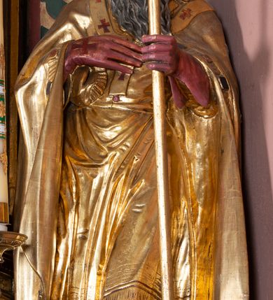 Zdjęcie nr 19: Nastawa ołtarzowa architektoniczna, jednoosiowa, jednokondygnacyjna ze zwieńczeniem. Ołtarz drewniany, prostopadłościenny. Mensa drewniana, o silnie wysuniętym gzymsie dekorowanego kostkowaniem. Antepedium w formie leżącego prostokąta z płyciną o dwóch wypukłych bokach. W polu płaskorzeźbione przedstawienie pelikana karmiącego w gnieździe młode, flankowanego winnym gronem i kłosami zbóż; płycina ujęta parą uskrzydlonych główek anielskich. Antepedium zamknięte profilowanym gzymsem, dekorowanym kostkowaniem, dźwigającym niepełne belkowanie. Tabernakulum prostopadłościenne, w formie drewnianej skrzynki obitej blachą miedzianą, ustawione na wysokim cokole ujętym od frontu i po bokach spływami wolutowymi, dźwigającymi wyłamany gzyms dekorowany kostkowaniem; na froncie płycina z rozetą. Drzwiczki w kształcie leżącego prostokąta zamkniętego łukiem segmentowym z aplikowanym kielichem z hostią, w otoczeniu winnego grona, na fakturowanym tle. Tabernakulum flankowane parą kanelowanych kolumienek, dźwigających gzyms wieńczący, dekorowany kostkowaniem oraz szczyt w formie zbliżonej do trójkąta, zamknięty gzymsem przechodzącym w przeciwstawnie zwrócone woluty, dekorowane kostkowaniem; w polu uskrzydlona główka anielska. 
Retabulum na zryzalitowanym przy brzegach cokole; ujęte dwiema parami kolumn o kapitelach kompozytowych i kanelowanych trzonach dźwigających pełne belkowanie oraz trójkątny przyczółek trójbocznie załamany; na nim, na osi podpór przerwany, wolutowy przyczółek, z leżącymi nań figurami. Szczyt w postaci dwustrefowego cokołu ujętego kartuszem z figurą św. Michała Archanioła. Pole środkowe w całości wypełnia płytka nisza ujęta profilowaną ramą z obrazem „Trójca Święta”, wymiennie z przedstawieniami Matki Boskiej z Dzieciątkiem i św. Katarzyny. Kondygnację flankują, ustawione na cokołach figury św. Stanisława i św. Wojciecha. Cokoły kolumn dekorowane płycinami z uskrzydlonymi główkami anielskimi; w polu cokołu płycina w formie wydłużonego, leżącego prostokąta o wypukłych bokach, z dekoracją schweifwerkową. Trzony kolumn dekorowane uskrzydlonymi główkami anielskimi podtrzymującymi festony utworzone z tkaniny i chwosty. Za kolumnami płyciny wypełnione schweifwerkiem, w ich centrum obelisk dekorowany cekinami i zwieńczony krzyżem. W partii fryzu od frontu uskrzydlone główki anielskie, po bokach schweifwerk. Pola obu przyczółków wypełnia ornament schweifwerkowy. Gzyms od spodu dekorowany rozetami; zwieńczony wolutowym kluczem dekorowanym schwrifwerkiem oraz uskrzydloną główką anielską. Woluty wieńczące zdobione palmetami. Kondygnacja ujęta uszami utworzonymi z ornamentu okuciowego i ulistnionych wolut. Struktura w całości złocona, płyciny i profile polichromowane na czerwono, uszaki na zielono. 