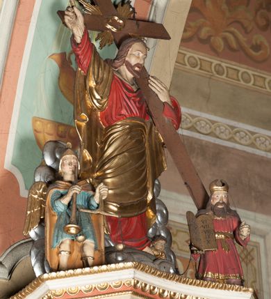 Zdjęcie nr 4: Ambona przyścienna wisząca, z dostępem od strony prezbiterium w postaci dwubiegowych schodów z podestem. Balustrada pełna, na cokole, dekorowana płycinami w formie rombów, z poręczą w postaci gzymsu. Kosz na planie kwadratu o ściętych narożach i wklęsłych bokach, na cokole w formie spłaszczonego wałka dekorowanego kampanulami w układzie poziomym. U spodu podwieszony odwrócony ostrosłup o ściętym wierzchołku i wklęsłych bokach ujęty w narożach spływami wolutowymi, dekorowany kampanulami, zakończony szyszką zdobioną cęgami. Ścianki kosza wydzielone pilastrami w formie wolut, których trzony dekorowane są ukwieconymi gałązkami. Na ściankach rocaille'owe płyciny z ornamentem roślinnym. Parapet w postaci gzymsu. Baldachim na planie analogicznym względem kosza, w formie gzymsu, dekorowany stylizowanym perełkowaniem, z podwieszonym lambrekinem. Na nim, na podstawie utworzonej z obłoków figura Chrystusa, zwróconego frontalnie, trzymającego na lewym ramieniu krzyż, z prawą ręką wskazującą w górę. Po jego lewej figurka Mojżesza z tablicami przykazań, po prawej św. Michała Archanioła trzymającego trąbę i wagę. Na podniebieniu baldachimu płaskorzeźbiona gołębica Ducha Świętego z czterema wiązkami promieni oraz dwie ukwiecone gałązki. Struktura polichromowana w kolorze beżowym, z białym detalem, ornamentyka i profile złocone, obłoki i gołębica srebrzone.