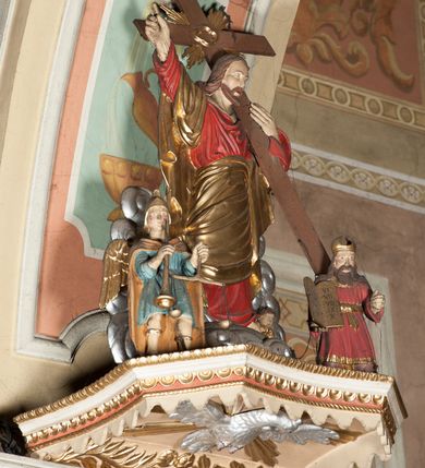 Zdjęcie nr 3: Ambona przyścienna wisząca, z dostępem od strony prezbiterium w postaci dwubiegowych schodów z podestem. Balustrada pełna, na cokole, dekorowana płycinami w formie rombów, z poręczą w postaci gzymsu. Kosz na planie kwadratu o ściętych narożach i wklęsłych bokach, na cokole w formie spłaszczonego wałka dekorowanego kampanulami w układzie poziomym. U spodu podwieszony odwrócony ostrosłup o ściętym wierzchołku i wklęsłych bokach ujęty w narożach spływami wolutowymi, dekorowany kampanulami, zakończony szyszką zdobioną cęgami. Ścianki kosza wydzielone pilastrami w formie wolut, których trzony dekorowane są ukwieconymi gałązkami. Na ściankach rocaille'owe płyciny z ornamentem roślinnym. Parapet w postaci gzymsu. Baldachim na planie analogicznym względem kosza, w formie gzymsu, dekorowany stylizowanym perełkowaniem, z podwieszonym lambrekinem. Na nim, na podstawie utworzonej z obłoków figura Chrystusa, zwróconego frontalnie, trzymającego na lewym ramieniu krzyż, z prawą ręką wskazującą w górę. Po jego lewej figurka Mojżesza z tablicami przykazań, po prawej św. Michała Archanioła trzymającego trąbę i wagę. Na podniebieniu baldachimu płaskorzeźbiona gołębica Ducha Świętego z czterema wiązkami promieni oraz dwie ukwiecone gałązki. Struktura polichromowana w kolorze beżowym, z białym detalem, ornamentyka i profile złocone, obłoki i gołębica srebrzone.