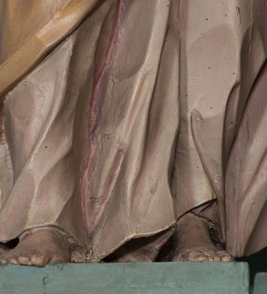 Zdjęcie nr 3: Rzeźba drążona, ustawiona na niewielkiej podstawie na planie kwadratu. Figura ukazana frontalnie, w kontrapoście, z głową przechyloną na prawy bark. Lewą rękę ma ugiętą przy piersi, prawą wyciąga w bok. Twarz ma pociągłą, o starczych rysach, dużych oczach, lekko garbatym nosie i niewielkich ustach, okoloną długimi włosami, zakrytymi welonem. Ubrana jest w bladoróżową tunikę o pozłoconych brzegach rękawów, przepasaną pozłoconą szarfą, silnie drapowaną oraz jasnobrązowy płaszcz zawinięty na prawym ramieniu i otaczający postać w partii bioder, o ekspresyjnie kształtowanej tkaninie. Na głowie ma jasnobrązowy welon opadający na plecy. Polichromia ciała naturalistyczna. 