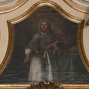 Zdjęcie nr 1: Obraz w formie trapezu o wklęsłych bokach, zamknięty faliście. W centrum kompozycji św. Jan Nepomucen ukazany do wysokości kolan, zwrócony frontalnie, z głową uniesioną do góry. Obiema rękami przytrzymuje krucyfiks oparty na jego lewym ramieniu. Twarz ma pociągłą, szczupłą, o rysach wydobytych głębokim światłocieniem, z oczami skierowanymi do góry, prostym nosem i pełnymi ustami, okoloną bujną brodą oraz włosami sięgającymi ramion. Wokół głowy świętego nimb i wieniec z pięciu gwiazd. Jan Nepomucen ubrany jest w białą komżę z wąskimi rękawami, lamowaną koronką, brązową almucję z różową podszewką zawiązaną u szyi niebieskim sznurem. W prawej części obrazu znajduje się stół przesłonięty zieloną tkaniną, z leżącymi na nim dwiema książkami. W górnej części dzieła ukazane ciemne niebo z zarysem obłoków, rozjaśnione wokół głowy świętego. Obraz ujęty profilowaną, pozłoconą ramą.