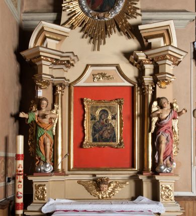 Zdjęcie nr 7: Nastawa architektoniczna, jednoosiowa, jednokondygnacyjna ze zwieńczeniem, ustawiona na wysokim dwustrefowym cokole. Ołtarz drewniany, prostopadłościenny z drewnianą mensą i kamiennym portatylem. Antepedium ujęte profilowaną ramą, w polu medalion z literą alfa. Retabulum ujęte dwiema parami pilastrów, przed wewnętrzną stoi para kolumn o kapitelach korynckich, przed zewnętrzną znajdują się figury aniołów. Podpory dźwigają pełne belkowanie, przerwane nad polem środkowym, nad figurami ustawione pod kątem imposty podtrzymywane przez muszle, dźwigające przerwany półkolisty przyczółek. Niemal całe pole środkowe wypełnia płycina w formie stojącego prostokąta o wklęsłych górnych narożach z dużo mniejszym obrazem Matki Boskiej Nieustającej Pomocy w osobnej ramie na czerwonym tle. Górna część płyciny dekorowana ornamentem roślinnym, u dołu, w partii predelli uskrzydlona główka anielska. Kondygnacja flankowana uszami utworzonymi z wolutowo skręconej wici roślinnej. Zwieńczenie w formie trapezu wypełnione niemal w całości owalnym medalionem z obrazem „Nawiedzenie św. Elżbiety”, ujętym otokiem z obłoków z uskrzydlonymi główkami anielskimi, w glorii promienistej. Struktura ołtarza polichromowana w kolorze beżowym, ornamentyka, profile i gloria pozłacane.