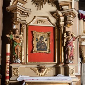 Zdjęcie nr 1: Nastawa architektoniczna, jednoosiowa, jednokondygnacyjna ze zwieńczeniem, ustawiona na wysokim dwustrefowym cokole. Ołtarz drewniany, prostopadłościenny z drewnianą mensą i kamiennym portatylem. Antepedium ujęte profilowaną ramą, w polu medalion z literą alfa. Retabulum ujęte dwiema parami pilastrów, przed wewnętrzną stoi para kolumn o kapitelach korynckich, przed zewnętrzną znajdują się figury aniołów. Podpory dźwigają pełne belkowanie, przerwane nad polem środkowym, nad figurami ustawione pod kątem imposty podtrzymywane przez muszle, dźwigające przerwany półkolisty przyczółek. Niemal całe pole środkowe wypełnia płycina w formie stojącego prostokąta o wklęsłych górnych narożach z dużo mniejszym obrazem Matki Boskiej Nieustającej Pomocy w osobnej ramie na czerwonym tle. Górna część płyciny dekorowana ornamentem roślinnym, u dołu, w partii predelli uskrzydlona główka anielska. Kondygnacja flankowana uszami utworzonymi z wolutowo skręconej wici roślinnej. Zwieńczenie w formie trapezu wypełnione niemal w całości owalnym medalionem z obrazem „Nawiedzenie św. Elżbiety”, ujętym otokiem z obłoków z uskrzydlonymi główkami anielskimi, w glorii promienistej. Struktura ołtarza polichromowana w kolorze beżowym, ornamentyka, profile i gloria pozłacane.