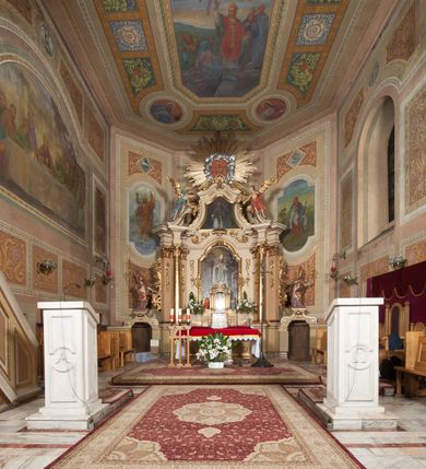 Zdjęcie nr 2: Nastawa ołtarzowa architektoniczna, jednoosiowa z bramkami, jednokondygnacyjna ze zwieńczeniem, na wysokim cokole. Ołtarz prostopadłościenny, mensa drewniana z marmurowym portatylem. Antepedium w formie leżącego prostokąta, ujęte profilowaną ramą. W jego polu trzy medaliony, w środkowym monogram IHS, w zewnętrznych alfa i omega, w narożach rocaille. Tabernakulum w formie prostopadłościennej metalowej skrzynki obitej fakturowaną blachą. Drzwiczki dwuskrzydłowe w kształcie stojącego prostokąta, w metalowych opaskach, z aplikowanymi, odlewanymi przedstawieniami krzyży ze zbożem i winnym gronem na fakturowanym tle. Tabernakulum w drewnianej obudowie stanowiącej dwustrefowy cokół dla tronu wstawienia, dekorowany płycinami z rozetami. Tron w formie obrotowej niszy w kształcie stojącego prostokąta zamkniętego łukiem półkolistym, ujętej dwiema parami kolumienek o kapitelach korynckich, dźwigających pełne belkowanie, przyjmujące nad niszą kształt łuku segmentowego o wypukłym licu. Na belkowaniu cokół ujęty w narożach spływami wolutowymi z figurą baranka apokaliptycznego na księdze.  
Nastawa flankowana dwiema parami pilastrów i parą filarów zewnętrznych ustawionych delikatnie pod kątem względem lica ołtarza, o trzonach dekorowanych rocaille&#039;m i zwisami kwiatowymi, przed nimi para kolumn o kapitelach kompozytowych. Podpory dźwigają pełne belkowanie, wyłamane na ich osi oraz przerwany, wolutowy przyczółek z figurami aniołów. Belkowanie przerwane nad polem środkowym, połączone architrawem przyjmującym kształt łuku nadwieszonego. W polu środkowym nisza w formie stojącego prostokąta zamkniętego łukiem półkolistym nadwieszonym z uskokiem z obrazem św. Stanisława, ujęta profilowaną ramą dekorowaną rocaille&#039;m. Nisza flankowana rocaille&#039;m i zwisami kwiatowymi. Kondygnacja ujęta uszami utworzonymi z rocaille&#039;u, wolut i dekoracji roślinnej. Zwieńczenie w formie zbliżonej do trapezu o wklęsłych bokach, zamknięte gzymsem przechodzącym w dwie zwrócone ku sobie woluty, zakończone medalionem z monogramem IHS w otoku z obłoków, w glorii promienistej. W polu obraz w formie analogicznej względem zwieńczenia z przedstawieniem św. Jana Nepomucena, ujęty w profilowaną ramę. U dołu dekorowany muszlą flankowaną przez ornament roślinny. Bramki z przejściami w formie stojącego prostokąta z nadprożem w kształcie cokołów, utworzonych z dwóch wolut, na których stoją figury św. Stanisława i św. Wojciecha. Struktura polichromowana w kolorze bladoróżowym, kapitele na różowo, ornamentyka, profile i kolumny pozłocone.