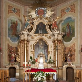 Zdjęcie nr 1: Nastawa ołtarzowa architektoniczna, jednoosiowa z bramkami, jednokondygnacyjna ze zwieńczeniem, na wysokim cokole. Ołtarz prostopadłościenny, mensa drewniana z marmurowym portatylem. Antepedium w formie leżącego prostokąta, ujęte profilowaną ramą. W jego polu trzy medaliony, w środkowym monogram IHS, w zewnętrznych alfa i omega, w narożach rocaille. Tabernakulum w formie prostopadłościennej metalowej skrzynki obitej fakturowaną blachą. Drzwiczki dwuskrzydłowe w kształcie stojącego prostokąta, w metalowych opaskach, z aplikowanymi, odlewanymi przedstawieniami krzyży ze zbożem i winnym gronem na fakturowanym tle. Tabernakulum w drewnianej obudowie stanowiącej dwustrefowy cokół dla tronu wstawienia, dekorowany płycinami z rozetami. Tron w formie obrotowej niszy w kształcie stojącego prostokąta zamkniętego łukiem półkolistym, ujętej dwiema parami kolumienek o kapitelach korynckich, dźwigających pełne belkowanie, przyjmujące nad niszą kształt łuku segmentowego o wypukłym licu. Na belkowaniu cokół ujęty w narożach spływami wolutowymi z figurą baranka apokaliptycznego na księdze.  
Nastawa flankowana dwiema parami pilastrów i parą filarów zewnętrznych ustawionych delikatnie pod kątem względem lica ołtarza, o trzonach dekorowanych rocaille&#039;m i zwisami kwiatowymi, przed nimi para kolumn o kapitelach kompozytowych. Podpory dźwigają pełne belkowanie, wyłamane na ich osi oraz przerwany, wolutowy przyczółek z figurami aniołów. Belkowanie przerwane nad polem środkowym, połączone architrawem przyjmującym kształt łuku nadwieszonego. W polu środkowym nisza w formie stojącego prostokąta zamkniętego łukiem półkolistym nadwieszonym z uskokiem z obrazem św. Stanisława, ujęta profilowaną ramą dekorowaną rocaille&#039;m. Nisza flankowana rocaille&#039;m i zwisami kwiatowymi. Kondygnacja ujęta uszami utworzonymi z rocaille&#039;u, wolut i dekoracji roślinnej. Zwieńczenie w formie zbliżonej do trapezu o wklęsłych bokach, zamknięte gzymsem przechodzącym w dwie zwrócone ku sobie woluty, zakończone medalionem z monogramem IHS w otoku z obłoków, w glorii promienistej. W polu obraz w formie analogicznej względem zwieńczenia z przedstawieniem św. Jana Nepomucena, ujęty w profilowaną ramę. U dołu dekorowany muszlą flankowaną przez ornament roślinny. Bramki z przejściami w formie stojącego prostokąta z nadprożem w kształcie cokołów, utworzonych z dwóch wolut, na których stoją figury św. Stanisława i św. Wojciecha. Struktura polichromowana w kolorze bladoróżowym, kapitele na różowo, ornamentyka, profile i kolumny pozłocone.