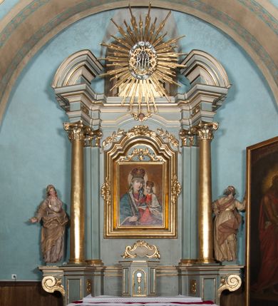 Zdjęcie nr 1: Nastawa architektoniczna, jednoosiowa, jednokondygnacyjna, ustawiona na wysokim cokole. Ołtarz w formie prostopadłościanu o ściętych z przodu narożach z prostokątną, drewnianą mensą, dekorowany trzema płycinami, na froncie monogram Marii ujęty winnym gronem. Na ołtarzu tabernakulum w formie prostopadłościennej skrzynki o ściętych przednich narożach, flankowanej parą pilastrów podtrzymujących gzyms. Drzwiczki w formie stojącego prostokąta zamkniętego półkoliście, ujęte profilowaną ramą, w polu płaskorzeźbiony kielich z hostią. 
Nastawa flankowana parą zwróconych na zewnątrz zdwojonych pilastrów i stojącą przed nimi parą kolumn o kapitelach kompozytowych. Podpory dźwigają pełne belkowanie z wyłamanym nad polem środkowym na kształt łuku odcinkowego gzymsem oraz przerwany, półkolisty przyczółek. Po zewnętrznej stronie kolumn dwie konsole, na których stoją figury św. Anny i św. Joachima. W polu głównym nisza w formie stojącego prostokąta zamkniętego łukiem półkolistym nadwieszonym z uskokiem, ujęta profilowaną ramą, dekorowana rocaille'em, wewnątrz mniejszy obraz Matki Boskiej z Dzieciątkiem w kształcie stojącego prostokąta. W przyłuczach niszy dwie ukwiecone gałązki, na gzymsie uskrzydlona główka anielska, u dołu rocaille'owy kartusz. W miejscu zwieńczenia, na tle okna zamontowany medalion z monogramem Marii w glorii promienistej. Struktura polichromowana w kolorze jasnoniebieskim z beżowymi detalami, ornamentyka, kolumny i profile pozłocone. 