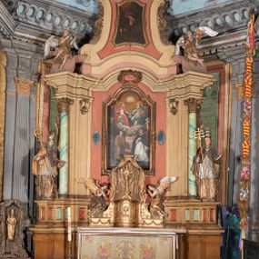 Zdjęcie nr 1: Ołtarz kamienny, prostopadłościenny, z kamienną mensą oraz antepedium w formie leżącego prostokąta z tkaniny, ujętym profilowaną, drewnianą i złoconą ramą. Na ołtarzu ustawione tabernakulum z tronem wystawienia. 
Nastawa architektoniczna, jednoosiowa, jednokondygnacyjna ze zwieńczeniem, ustawiona na dwustrefowym cokole ze skrajnie wyłamanymi pod kątem trzema parami prostopadłościanów. Retabulum ujęte ustawionymi pod kątem na zewnątrz filarami, opilastrowanymi po wewnętrznej stronie oraz stojącą przed nimi parą kolumn o kapitelach kompozytowych. Na skrajnie wyłamanych fragmentach cokołu ustawione figury świętego biskupa i świętego papieża. Podpory dźwigają pełne belkowanie połączone nad polem głównym wyłącznie gzymsem wyłamanym na kształt łuku odcinkowego nadwieszonego. Na osi kolumn, na belkowaniu fragmenty przerwanego falistego przyczółka, skierowane do wewnątrz, na których znajdują się dwie figury siedzących aniołów. W polu głównym wnęka w formie stojącego prostokąta zamkniętego łukiem półkolistym nadwieszonym z uskokiem, ujęta profilowaną ramą dekorowaną rocaille&#039;m. W niej zamontowany obraz Trójcy Świętej ze św. Franciszkiem i św. Dominikiem. Ponad wnęką rokokowy kartusz z napisem w polu: „S[anctus] S[anctus] S[anctus]”. Po bokach wnęki dwa pola w kształcie rombów o ściętych kątach z wprawionymi lustrami. Zwieńczenie w formie zbliżonej do trapezu ujętego spływami wolutowymi, zamkniętego fragmentem falistego gzymsu, dekorowane z trzech stron rocaille&#039;m. W polu zwieńczenia płycina o tej samej formie, wewnątrz obraz św. Marii Magdaleny w kształcie zbliżonym do trapezu o ściętych dolnych narożach, ujęty profilowaną ramą dekorowaną rocaille&#039;m. Struktura polichromowana w odcieniach beżu, partiami zaś różu i jasnej czerwieni; płyciny cokołu i trzony kolumn polichromowane na sposób imitujący marmoryzację w odcieniach zieleni, niektóre płyciny również czerwieni. Profile i ornamentyka złocone.
