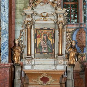 Zdjęcie nr 1: Mensa drewniana; ołtarz sarkofagowy, o wklęsłych bokach, zwężających się ku dołowi, ustawiony na niskim cokole zakończonym podwójnym półwałkiem, dekorowany rocaille'owym kartuszem. Ołtarz ustawiony na trzech drewnianych stopniach.
Retabulum jednoosiowe, jednokondygnacyjne, z niskim dwustrefowym cokołem z wyłamanymi dwoma sześcianami, stanowiącymi cokoły. Nastawa ołtarzowa ujęta parą kolumn kompozytowych ustawionych na tle zwielokrotnionych pilastrów. Podpory wspierają pełne belkowanie z wyłamanymi impostami na osi kolumn, na których znajdują się fragmenty wolutowego przerwanego przyczółka, na których siedzą dwa putta. Zwieńczenie ułamane, nad nim zamontowana gloria promienista z obłokami i dwiema uskrzydlonymi główkami anielskimi. W polu środkowym obraz w formie stojącego prostokąta z przedstawieniem Matki Boskiej z Dzieciątkiem. Nastawa dekorowana ornamentem o motywach roślinnych i cęgowych w partii cokołu, pilastrów i belkowania, na impostach dwie rozety. Retabulum ujęte uszami utworzonymi z ornamentu rocaille'owego i motywów roślinnych. Po bokach ołtarza dostawione cokoły, na których ustawione figury św. Wojciecha i św. Stanisława. Struktura nastawy polichromowana w kolorze białym, profile, kolumny, gloria i ornamentyka złocone.

