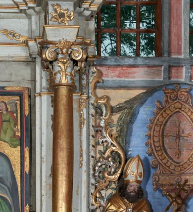 Zdjęcie nr 5: Mensa drewniana; ołtarz sarkofagowy, o wklęsłych bokach, zwężających się ku dołowi, ustawiony na niskim cokole zakończonym podwójnym półwałkiem, dekorowany rocaille'owym kartuszem. Ołtarz ustawiony na trzech drewnianych stopniach.
Retabulum jednoosiowe, jednokondygnacyjne, z niskim dwustrefowym cokołem z wyłamanymi dwoma sześcianami, stanowiącymi cokoły. Nastawa ołtarzowa ujęta parą kolumn kompozytowych ustawionych na tle zwielokrotnionych pilastrów. Podpory wspierają pełne belkowanie z wyłamanymi impostami na osi kolumn, na których znajdują się fragmenty wolutowego przerwanego przyczółka, na których siedzą dwa putta. Zwieńczenie ułamane, nad nim zamontowana gloria promienista z obłokami i dwiema uskrzydlonymi główkami anielskimi. W polu środkowym obraz w formie stojącego prostokąta z przedstawieniem Matki Boskiej z Dzieciątkiem. Nastawa dekorowana ornamentem o motywach roślinnych i cęgowych w partii cokołu, pilastrów i belkowania, na impostach dwie rozety. Retabulum ujęte uszami utworzonymi z ornamentu rocaille'owego i motywów roślinnych. Po bokach ołtarza dostawione cokoły, na których ustawione figury św. Wojciecha i św. Stanisława. Struktura nastawy polichromowana w kolorze białym, profile, kolumny, gloria i ornamentyka złocone.

