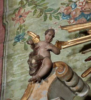 Zdjęcie nr 7: Mensa drewniana; ołtarz sarkofagowy, o wklęsłych bokach, zwężających się ku dołowi, ustawiony na niskim cokole zakończonym podwójnym półwałkiem, dekorowany rocaille'owym kartuszem. Ołtarz ustawiony na trzech drewnianych stopniach.
Retabulum jednoosiowe, jednokondygnacyjne, z niskim dwustrefowym cokołem z wyłamanymi dwoma sześcianami, stanowiącymi cokoły. Nastawa ołtarzowa ujęta parą kolumn kompozytowych ustawionych na tle zwielokrotnionych pilastrów. Podpory wspierają pełne belkowanie z wyłamanymi impostami na osi kolumn, na których znajdują się fragmenty wolutowego przerwanego przyczółka, na których siedzą dwa putta. Zwieńczenie ułamane, nad nim zamontowana gloria promienista z obłokami i dwiema uskrzydlonymi główkami anielskimi. W polu środkowym obraz w formie stojącego prostokąta z przedstawieniem Matki Boskiej z Dzieciątkiem. Nastawa dekorowana ornamentem o motywach roślinnych i cęgowych w partii cokołu, pilastrów i belkowania, na impostach dwie rozety. Retabulum ujęte uszami utworzonymi z ornamentu rocaille'owego i motywów roślinnych. Po bokach ołtarza dostawione cokoły, na których ustawione figury św. Wojciecha i św. Stanisława. Struktura nastawy polichromowana w kolorze białym, profile, kolumny, gloria i ornamentyka złocone.

