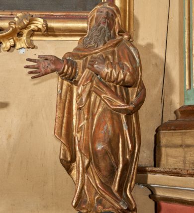 Zdjęcie nr 1: Figura nieopracowana od tyłu; ustawiona na niskiej, nieregularnej podstawie. Święty ukazany frontalnie, z głową przechyloną na lewe ramię, z ugiętą lewą nogą, prawą rękę wyciąga w bok, lewą kładzie na piersi. Twarz ma pociągłą, o niskim czole, niewielkich, wąskich oczach, dużym nosie, pełnych ustach, okoloną długą, falowaną brodą. Ubrany jest w złoconą tunikę przepasaną w talii oraz złocony płaszcz zarzucony na ramiona i głowę, zapięty na lewym ramieniu klamrą w formie kuli, z połą płaszcza podtrzymywaną z przodu postaci. Polichromia ciała naturalistyczna, szaty złocone.

