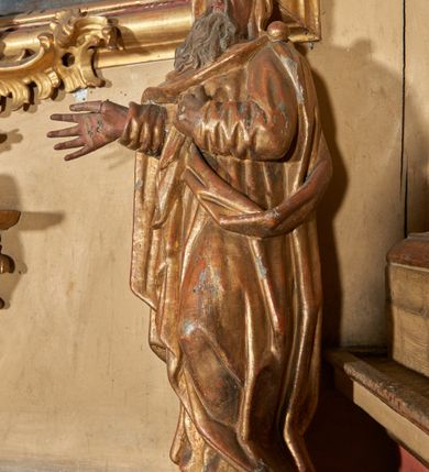 Zdjęcie nr 3: Figura nieopracowana od tyłu; ustawiona na niskiej, nieregularnej podstawie. Święty ukazany frontalnie, z głową przechyloną na lewe ramię, z ugiętą lewą nogą, prawą rękę wyciąga w bok, lewą kładzie na piersi. Twarz ma pociągłą, o niskim czole, niewielkich, wąskich oczach, dużym nosie, pełnych ustach, okoloną długą, falowaną brodą. Ubrany jest w złoconą tunikę przepasaną w talii oraz złocony płaszcz zarzucony na ramiona i głowę, zapięty na lewym ramieniu klamrą w formie kuli, z połą płaszcza podtrzymywaną z przodu postaci. Polichromia ciała naturalistyczna, szaty złocone.

