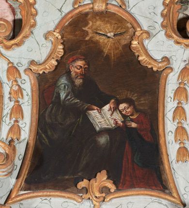 Zdjęcie nr 1: Obraz w formie stojącego prostokąta, o wklęsłych bokach, zamknięty łukiem odcinkowym z uskokiem. W centrum scena ukazująca św. Joachima uczącego Marię przedstawioną jako dziecko. Święty w lewej części obrazu, siedzący w fotelu, zwrócony w trzech czwartych w lewo, z lekko pochyloną głową. Prawą ręką przytrzymuje na kolanach otwartą księgę, lewą zaś wskazuje na tekst w niej zawarty. Twarz ma pociągłą, szczupłą, o starczych rysach, łukowatych brwiach, okrągłych oczach skierowanych w dół, wąskim, garbatym nosie i wąskich ustach; okoloną długą siwą brodą oraz krótkimi włosami. Na głowie ma czerwone nakrycie głowy, ponad nią nimb. Ubrany jest w obfitą, niebieską tunikę, przepasaną w talii oraz zielony płaszcz zarzucony przez lewe przedramię i opadający na kolana. W prawej części obrazu, przed św. Joachimem, ukazana Maria w pozycji stojącej, zwrócona w trzech czwartych w prawo, z pochyloną głową. Obie ręce ma uniesione, prawą dłonią, w geście wskazującym, dotyka księgi. Twarz ma okrągłą, o uniesionych brwiach, okrągłych oczach skierowanych w dół, małym prostym nosie i ustach. Włosy ma długie i brązowe, opadające na plecy. Ubrana jest w długą, czerwoną suknię oraz niebieski płaszcz przerzucony diagonalnie przez prawe ramię. W górnej części obrazu, pośród rozświetlonych obłoków ukazana gołębica Ducha Świętego w glorii promienistej. Postacie ukazane na neutralnym, brązowym tle. 






