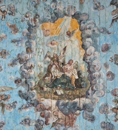 Zdjęcie nr 3: Ściany prezbiterium dekorowane malowanymi zielono-różowymi płycinami w formie stojących prostokątów, ujętymi iluzjonistycznymi ramkami, z malowaną dekoracją w formie kwiatowych festonów w górnej części oraz fantazyjnych dekoracji roślinno-kandelabrowych i wazonów z ornamentem roślinnym w dolnej. Płyciny umieszczone są między oknami ujętymi w malowane prostokątne opaski, pod którymi znajdują się zacheuszki. Na południowej ścianie znajdują się dwa okna, na północnej dwa pozorne okna, z których jedno przesłania ambona. Zacheuszki w formie malowanych migdałowatych medalionów z krzyżami w polach, na iluzjonistycznych wspornikach o klasycyzującej dekoracji, na tle niebieskich owalnych medalionów ujętych u góry wieńcem laurowym i u dołu dekoracją roślinną. Prezbiterium zamknięte trójbocznie, z podkreślonymi polichromią dwiema parami zwielokrotnionych pilastrów, flankujących ołtarz główny. Za ołtarzem, na każdej z trzech ścian analogicznie malowane płyciny. Dolny pas wszystkich ścian prezbiterium opasuje malowany iluzjonistycznie jasnobrązowy i marmoryzowany cokół, dekorowany płycinami w formie leżącego prostokąta i zamknięty profilowaniem. Ściany prezbiterium zamknięte od góry drewnianym gzymsem pokrytym malowanymi iluzjonistycznie elementami profili z kostkowaniem i jajownikiem.
Sklepienie w części prezbiterialnej w formie malowanego nieba, wypełnionego obłokami. Nad gzymsem malowana iluzjonistycznie kamienna balustrada z ośmioma wazonami na cokołach umieszczonych na osiach wydzielających podziały ścian prezbiterium, z motywem stylizowanego biegnącego psa stanowiącym wypełnienie balustrady. Pomiędzy wazonami ukazani jako stojący za balustradą i widoczni w półpostaci aniołowie. Na północnej ścianie anioł trzymający w dłoniach zamknięta koronę, z napisem „PRINCIPATUS” oraz anioł ubrany w zbroję i hełm z białą chorągwią w prawej ręce, podpisany „ARCHANGELI”. Na południowej ścianie anioł ubrany w suknię i płaszcz, który prawą ręką wskazuje niebo, lewą zaś tuli do siebie dziecko, podpisany „ANGELI” oraz anioł ubrany w suknię i płaszcz, który lewą rękę kładzie na piersi, w prawej trzyma miecz skierowany ostrzem w dół, podpisany „DOMINATIONES”. W centralnej części sklepienia ujęta obłokami z malowanym u dołu aniołem scena ekstazy św. Marii Magdaleny. Ukazuje ona omdlewającą na skałach świętą, której towarzyszą aniołowie. Maria Magdalena przedstawiona z profilu, jako siedząca, odchylona w tył, z opadającą głową i rękami. Ubrana w biało-niebieską suknię odsłaniającą ramiona. Włosy ma długie, opadające na plecy i pierś. Nad głową nimb. Za nią i obok niej siedzą dwaj aniołowie, który podtrzymują jej opadające ciało. Przy prawym boku świętej znajduje się krucyfiks, natomiast w dolnej części sceny, na ziemi leżą: czaszka, dyscyplina, otwarta księga i puszka na wonności. W górnej części sceny ukazane rozświetlone niebo, z którego wyłania się wiązka światła, a wokół ukazane są trzy uskrzydlone główki anielskie. Na ścianie zachodniej prezbiterium, nad łukiem tęczowym napis: „Roku Pańskiego 1565 kościół ten zbudowany przez wielmożnego Pana Spytka Jordana, poświęcony przez najjaśniejszego i przewielebnego Pana Tomasza Oborskiego, Biskupa Loadycejskiego, Syfragana Krakowskiego w Roku Pańskim 1634 w dniu 5 czerwca. Odnowiony całkowicie i ozdobiony ołtarzami wraz z organami i chórem przez plebana w Roku pańskim 1778. Odmalowany zaś kosztem tegoż plebana w Roku Pańskim 1802. A[ndrzej] A[ntałkiewicz]”. Za ołtarzem głównym drugi napis: „Restau/rata Hoc / Ecclesia / AD 1777 / Finita 23 / Septembris”.
W korpusie nawowym polichromia o analogicznej formie. Na ścianach północnej i południowej malowane płyciny pomiędzy oknami, okna w malowanych opaskach z zacheuszkami w formie medalionów poniżej. Ściana tęczowa zdobiona malowanymi płycinami, łuk ujęty malowanym en grisaille owocowo-kwiatowym festonem, opadającym na wsporniki z malowanymi iluzjonistycznie elementami architektonicznymi. Ściana zachodnia w dolnej partii malowana analogicznie do ścian bocznych. Natomiast w górnej partii, od poziomu parapetu chóru muzycznego malowana iluzjonistycznie architektura w postaci opilastrowanego muru kamiennego i arkady pośrodku z apsydą o podziałach pilastrowych z malowanymi oknami, na której tle umieszczony jest organ. Zaskrzynienia z malowanymi prostokątnymi płycinami. Filary podtrzymujące zaskrzynienia malowane na sposób imitujący marmoryzację. Podpory podtrzymujące drewniany profilowany gzyms pokryty malowanymi iluzjonistycznie elementami profili z kostkowaniem i jajownikiem. Powyżej sklepienie z malowaną iluzjonistycznie balustradą, z trzech stron (północnej, wschodniej i południowej), analogiczną jak w prezbiterium, z wazonami na cokołach umieszczonymi na osiach podpór i z postaciami. Na ścianie północnej anioł trzymający w dłoniach koronę cierniową z podpisem „VIRTUTES”, anioł trzymający księgę i berło, z podpisem „SERAFIN” oraz anioł trzymający berło, bez podpisu. Na ścianie południowej anioł trzymający buławę, z napisem „POTESTATES”, anioł trzymający miecz skierowany w górę, z napisem „CHERUBIN” i wizerunek św. Franciszka serafickiego podczas stygmatyzacji. Na sklepieniu nawy przedstawione niebo wypełnione obłokami, pośrodku scena Koronacji Najświętszej Marii Panny, zamknięta owalem i otoczona obłokami. Scena ukazuje Chrystusa i Boga Ojca tronujących pośród obłoków z gołębicą Ducha Świętego w glorii promienistej unoszącą się nad nimi. Obaj trzymają koronę nad głową klęczącej poniżej Marii, której nogi spoczywają na globie i sierpie księżyca, a która stopami depcze węża. Grupa otoczona uskrzydlonymi główkami anielskimi, dwoma puttami i aniołem trzymającym w dłoni lilię. 
