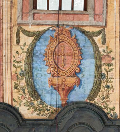 Zdjęcie nr 4: Ściany prezbiterium dekorowane malowanymi zielono-różowymi płycinami w formie stojących prostokątów, ujętymi iluzjonistycznymi ramkami, z malowaną dekoracją w formie kwiatowych festonów w górnej części oraz fantazyjnych dekoracji roślinno-kandelabrowych i wazonów z ornamentem roślinnym w dolnej. Płyciny umieszczone są między oknami ujętymi w malowane prostokątne opaski, pod którymi znajdują się zacheuszki. Na południowej ścianie znajdują się dwa okna, na północnej dwa pozorne okna, z których jedno przesłania ambona. Zacheuszki w formie malowanych migdałowatych medalionów z krzyżami w polach, na iluzjonistycznych wspornikach o klasycyzującej dekoracji, na tle niebieskich owalnych medalionów ujętych u góry wieńcem laurowym i u dołu dekoracją roślinną. Prezbiterium zamknięte trójbocznie, z podkreślonymi polichromią dwiema parami zwielokrotnionych pilastrów, flankujących ołtarz główny. Za ołtarzem, na każdej z trzech ścian analogicznie malowane płyciny. Dolny pas wszystkich ścian prezbiterium opasuje malowany iluzjonistycznie jasnobrązowy i marmoryzowany cokół, dekorowany płycinami w formie leżącego prostokąta i zamknięty profilowaniem. Ściany prezbiterium zamknięte od góry drewnianym gzymsem pokrytym malowanymi iluzjonistycznie elementami profili z kostkowaniem i jajownikiem.
Sklepienie w części prezbiterialnej w formie malowanego nieba, wypełnionego obłokami. Nad gzymsem malowana iluzjonistycznie kamienna balustrada z ośmioma wazonami na cokołach umieszczonych na osiach wydzielających podziały ścian prezbiterium, z motywem stylizowanego biegnącego psa stanowiącym wypełnienie balustrady. Pomiędzy wazonami ukazani jako stojący za balustradą i widoczni w półpostaci aniołowie. Na północnej ścianie anioł trzymający w dłoniach zamknięta koronę, z napisem „PRINCIPATUS” oraz anioł ubrany w zbroję i hełm z białą chorągwią w prawej ręce, podpisany „ARCHANGELI”. Na południowej ścianie anioł ubrany w suknię i płaszcz, który prawą ręką wskazuje niebo, lewą zaś tuli do siebie dziecko, podpisany „ANGELI” oraz anioł ubrany w suknię i płaszcz, który lewą rękę kładzie na piersi, w prawej trzyma miecz skierowany ostrzem w dół, podpisany „DOMINATIONES”. W centralnej części sklepienia ujęta obłokami z malowanym u dołu aniołem scena ekstazy św. Marii Magdaleny. Ukazuje ona omdlewającą na skałach świętą, której towarzyszą aniołowie. Maria Magdalena przedstawiona z profilu, jako siedząca, odchylona w tył, z opadającą głową i rękami. Ubrana w biało-niebieską suknię odsłaniającą ramiona. Włosy ma długie, opadające na plecy i pierś. Nad głową nimb. Za nią i obok niej siedzą dwaj aniołowie, który podtrzymują jej opadające ciało. Przy prawym boku świętej znajduje się krucyfiks, natomiast w dolnej części sceny, na ziemi leżą: czaszka, dyscyplina, otwarta księga i puszka na wonności. W górnej części sceny ukazane rozświetlone niebo, z którego wyłania się wiązka światła, a wokół ukazane są trzy uskrzydlone główki anielskie. Na ścianie zachodniej prezbiterium, nad łukiem tęczowym napis: „Roku Pańskiego 1565 kościół ten zbudowany przez wielmożnego Pana Spytka Jordana, poświęcony przez najjaśniejszego i przewielebnego Pana Tomasza Oborskiego, Biskupa Loadycejskiego, Syfragana Krakowskiego w Roku Pańskim 1634 w dniu 5 czerwca. Odnowiony całkowicie i ozdobiony ołtarzami wraz z organami i chórem przez plebana w Roku pańskim 1778. Odmalowany zaś kosztem tegoż plebana w Roku Pańskim 1802. A[ndrzej] A[ntałkiewicz]”. Za ołtarzem głównym drugi napis: „Restau/rata Hoc / Ecclesia / AD 1777 / Finita 23 / Septembris”.
W korpusie nawowym polichromia o analogicznej formie. Na ścianach północnej i południowej malowane płyciny pomiędzy oknami, okna w malowanych opaskach z zacheuszkami w formie medalionów poniżej. Ściana tęczowa zdobiona malowanymi płycinami, łuk ujęty malowanym en grisaille owocowo-kwiatowym festonem, opadającym na wsporniki z malowanymi iluzjonistycznie elementami architektonicznymi. Ściana zachodnia w dolnej partii malowana analogicznie do ścian bocznych. Natomiast w górnej partii, od poziomu parapetu chóru muzycznego malowana iluzjonistycznie architektura w postaci opilastrowanego muru kamiennego i arkady pośrodku z apsydą o podziałach pilastrowych z malowanymi oknami, na której tle umieszczony jest organ. Zaskrzynienia z malowanymi prostokątnymi płycinami. Filary podtrzymujące zaskrzynienia malowane na sposób imitujący marmoryzację. Podpory podtrzymujące drewniany profilowany gzyms pokryty malowanymi iluzjonistycznie elementami profili z kostkowaniem i jajownikiem. Powyżej sklepienie z malowaną iluzjonistycznie balustradą, z trzech stron (północnej, wschodniej i południowej), analogiczną jak w prezbiterium, z wazonami na cokołach umieszczonymi na osiach podpór i z postaciami. Na ścianie północnej anioł trzymający w dłoniach koronę cierniową z podpisem „VIRTUTES”, anioł trzymający księgę i berło, z podpisem „SERAFIN” oraz anioł trzymający berło, bez podpisu. Na ścianie południowej anioł trzymający buławę, z napisem „POTESTATES”, anioł trzymający miecz skierowany w górę, z napisem „CHERUBIN” i wizerunek św. Franciszka serafickiego podczas stygmatyzacji. Na sklepieniu nawy przedstawione niebo wypełnione obłokami, pośrodku scena Koronacji Najświętszej Marii Panny, zamknięta owalem i otoczona obłokami. Scena ukazuje Chrystusa i Boga Ojca tronujących pośród obłoków z gołębicą Ducha Świętego w glorii promienistej unoszącą się nad nimi. Obaj trzymają koronę nad głową klęczącej poniżej Marii, której nogi spoczywają na globie i sierpie księżyca, a która stopami depcze węża. Grupa otoczona uskrzydlonymi główkami anielskimi, dwoma puttami i aniołem trzymającym w dłoni lilię. 
