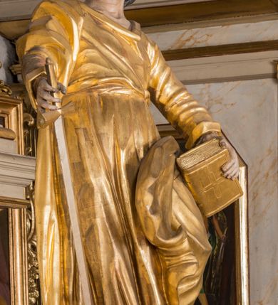 Zdjęcie nr 2: Figura ścięta z tyłu, drążona. Święty ukazany frontalnie, z uniesioną głową skierowaną w prawo, w kontrapoście, o esowato wygiętej sylwetce, odchylonej lekko w tył. W prawej ręce trzyma miecz, zwrócony ostrzem w dół, lewą przytrzymuje na nodze księgę. Twarz ma pociągłą, o dużych, migdałowatych oczach, zadartym nosie i pełnych ustach z wysuniętą górną wargą. Twarz okolona krótką, rozwidloną brodą oraz falowanymi włosami opadającymi na kark. Święty ubrany jest w sięgającą stóp tunikę z długimi rękawami, przepasaną szarfą oraz płaszcz zwinięty wokół prawego ramienia i opadający na lewą nogę. Polichromia ciała naturalistyczna, szaty i atrybuty złocone, detal srebrzony.