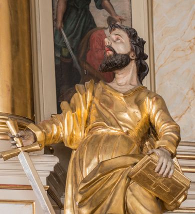 Zdjęcie nr 6: Figura ścięta z tyłu, drążona. Święty ukazany frontalnie, z uniesioną głową skierowaną w prawo, w kontrapoście, o esowato wygiętej sylwetce, odchylonej lekko w tył. W prawej ręce trzyma miecz, zwrócony ostrzem w dół, lewą przytrzymuje na nodze księgę. Twarz ma pociągłą, o dużych, migdałowatych oczach, zadartym nosie i pełnych ustach z wysuniętą górną wargą. Twarz okolona krótką, rozwidloną brodą oraz falowanymi włosami opadającymi na kark. Święty ubrany jest w sięgającą stóp tunikę z długimi rękawami, przepasaną szarfą oraz płaszcz zwinięty wokół prawego ramienia i opadający na lewą nogę. Polichromia ciała naturalistyczna, szaty i atrybuty złocone, detal srebrzony.