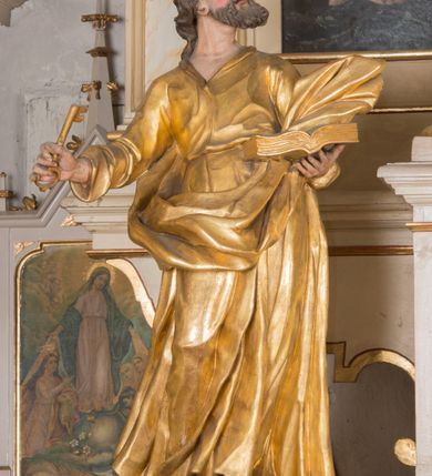 Zdjęcie nr 3: Figura ścięta z tyłu, drążona, ustawiona na niskiej podstawie. Święty ukazany frontalnie, z głową skierowaną w lewo, stoi w kontrapoście. Lewą ręką podtrzymuje otwartą księgę, prawą wyciąga w bok, a w dłoni trzyma klucz. Twarz ma pociągłą, o starczych rysach, migdałowatych oczach skierowanych w górę, lekko garbatym nosie oraz otwartych ustach z widoczną linią zębów. Okolona jest brodą, silnie wysuniętą do przodu oraz krótkimi, kręconymi włosami. Ubrany jest w tunikę z kołnierzykiem, przepasaną w talii, ściśle przylegającą do ciała w partii torsu oraz płaszcz przepasany diagonalnie przez lewe ramię i otaczający postać z wywiniętą połą na prawym boku. Polichromia ciała naturalistyczna, włosy ciemnobrązowe, szaty i atrybuty złocone. 

