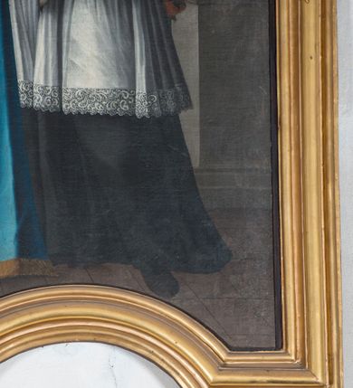 Zdjęcie nr 4: Obraz w formie stojącego prostokąta zamkniętego łukiem falistym, z wyciętym półkolem w dolnym boku. W centrum kompozycji św. Jan Nepomucen ukazany w całej postaci, zwrócony w trzech czwartych w prawo, w kontrapoście. W prawej, ugiętej ręce trzyma język w glorii promienistej, na kciuku ma zawieszone dwa klucze, zaś lewą dłonią wskazuje na nie. Twarz ma pociągłą, o wystających kościach policzkowych, migdałowatych oczach, prostym nosie i pełnych ustach, okoloną puszystą brodą oraz falowanymi włosami sięgającymi ramion. Wokół głowy ma glorię gwiaździstą i nimb. Ubrany jest w czarną sutannę, białą komżę lamowaną koronką oraz almucję. Święty stoi przed stołem nakrytym niebieską tkaniną z frędzlą, na nim znajduje się krucyfiks i otwarta księga. Nad nim, na tle obłoków unosi się putto trzymające wieniec laurowy i liść palmy. Postać ukazana we wnętrzu, z widocznym w prawej części obrazu filarem owiniętym zieloną draperią. Obraz ujęty profilowaną ramą dekorowaną po bokach rocaille&#039;m. 




