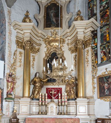 Zdjęcie nr 2: Nastawa ołtarzowa architektoniczna, jednoosiowa, jednokondygnacyjna ze zwieńczeniem, ustawiona na dwustrefowym cokole z wyodrębnionymi prostopadłościanami. Ołtarz kamienny, prostopadłościenny, w drewnianej obudowie. Mensa kamienna z marmurowym portatylem. Antepedium drewniane, w kształcie leżącego prostokąta, ujęte profilowaną ramą, z płaskorzeźbionym monogram IHS w glorii oraz fragmentami ornamentu roślinnego. Tabernakulum w formie prostopadłościennej skrzynki o wypukłym licu, flankowanej parą kolumienek na cokołach, ustawionych pod kątem, dźwigających woluty oraz gzyms przyjmujący formę łuku segmentowego nadwieszonego. Drzwiczki w kształcie stojącego prostokąta zamkniętego łukiem półkolistym, w opasce, z płaskorzeźbionym przedstawieniem baranka apokaliptycznego, leżącego na księdze, w glorii. Nastawa ujęta dwiema parami pilastrów dekorowanych rocaille'em i stojącą pomiędzy nimi parą kolumn o kapitelach kompozytowych dźwigających pełne belkowanie, wyłamane na ich osi, przerwane pośrodku. Na belkowaniu ustawione dwa wazony. W polu centralnym głęboka wnęka w formie stojącego prostokąta zamkniętego łukiem półkolistym nadwieszonym z uskokiem, ujęta profilowaną ramą, z obrazem św. Małgorzaty w osobnej profilowanej ramie o kształcie stojącego prostokąta zamkniętego ornamentalnym łukiem. Ponad nią, w partii belkowania rokokowy kartusz z rytą koroną i liśćmi palmy, a poniżej prostokątna płycina z wotami. Pole flankowane figurami św. Jana Ewangelisty i Matki Boskiej stojącymi na ćwierćkolistych cokołach. Nastawa ujęta uszami utworzonymi z rocaille'u. Zwieńczenie w formie stojącego prostokąta o wklęsłych bokach, ze spływami z uszakami po bokach, zamknięte gzymsem przyjmującym formę łuku segmentowego nadwieszonego z uskokiem, wyłamanego przy brzegach, dekorowanego rocaille'em. W polu obraz św. Małgorzaty ujęty profilowaną ramą w kształcie stojącego prostokąta zamkniętego łukiem segmentowym nadwieszonym z uskokiem. 
Struktura marmoryzowana w kolorze beżowym; ornamentyka, profile i kolumny złocone.