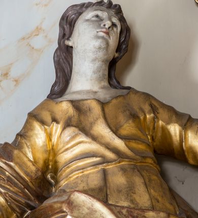 Zdjęcie nr 16: Nastawa ołtarzowa architektoniczna, jednoosiowa, jednokondygnacyjna ze zwieńczeniem, ustawiona na dwustrefowym cokole z wyodrębnionymi prostopadłościanami. Ołtarz kamienny, prostopadłościenny, w drewnianej obudowie. Mensa kamienna z marmurowym portatylem. Antepedium drewniane, w kształcie leżącego prostokąta, ujęte profilowaną ramą, z płaskorzeźbionym monogram IHS w glorii oraz fragmentami ornamentu roślinnego. Tabernakulum w formie prostopadłościennej skrzynki o wypukłym licu, flankowanej parą kolumienek na cokołach, ustawionych pod kątem, dźwigających woluty oraz gzyms przyjmujący formę łuku segmentowego nadwieszonego. Drzwiczki w kształcie stojącego prostokąta zamkniętego łukiem półkolistym, w opasce, z płaskorzeźbionym przedstawieniem baranka apokaliptycznego, leżącego na księdze, w glorii. Nastawa ujęta dwiema parami pilastrów dekorowanych rocaille&#039;em i stojącą pomiędzy nimi parą kolumn o kapitelach kompozytowych dźwigających pełne belkowanie, wyłamane na ich osi, przerwane pośrodku. Na belkowaniu ustawione dwa wazony. W polu centralnym głęboka wnęka w formie stojącego prostokąta zamkniętego łukiem półkolistym nadwieszonym z uskokiem, ujęta profilowaną ramą, z obrazem św. Małgorzaty w osobnej profilowanej ramie o kształcie stojącego prostokąta zamkniętego ornamentalnym łukiem. Ponad nią, w partii belkowania rokokowy kartusz z rytą koroną i liśćmi palmy, a poniżej prostokątna płycina z wotami. Pole flankowane figurami św. Jana Ewangelisty i Matki Boskiej stojącymi na ćwierćkolistych cokołach. Nastawa ujęta uszami utworzonymi z rocaille&#039;u. Zwieńczenie w formie stojącego prostokąta o wklęsłych bokach, ze spływami z uszakami po bokach, zamknięte gzymsem przyjmującym formę łuku segmentowego nadwieszonego z uskokiem, wyłamanego przy brzegach, dekorowanego rocaille&#039;em. W polu obraz św. Małgorzaty ujęty profilowaną ramą w kształcie stojącego prostokąta zamkniętego łukiem segmentowym nadwieszonym z uskokiem. 
Struktura marmoryzowana w kolorze beżowym; ornamentyka, profile i kolumny złocone.