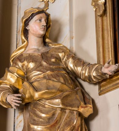 Zdjęcie nr 10: Nastawa ołtarzowa architektoniczna, jednoosiowa, jednokondygnacyjna ze zwieńczeniem, ustawiona na dwustrefowym cokole z wyodrębnionymi prostopadłościanami. Ołtarz kamienny, prostopadłościenny, w drewnianej obudowie. Mensa kamienna z marmurowym portatylem. Antepedium drewniane, w kształcie leżącego prostokąta, ujęte profilowaną ramą, z płaskorzeźbionym monogramem maryjnym oraz fragmentami ornamentu roślinnego. Tabernakulum w kształcie prostopadłościennej skrzynki o wypukłym licu, flankowanej parą kolumienek na cokołach, ustawionych pod kątem, dźwigających woluty oraz gzyms przyjmujący formę łuku segmentowego nadwieszonego. Drzwiczki w kształcie stojącego prostokąta zamkniętego łukiem półkolistym, w opasce, z płaskorzeźbionym przedstawieniem baranka apokaliptycznego, leżącego na księdze, w glorii. Nastawa ujęta dwiema parami pilastrów dekorowanych rocaille&#039;em i stojącą pomiędzy nimi parą kolumn o kapitelach kompozytowych dźwigających pełne belkowanie, wyłamane na ich osi, przerwane pośrodku. Na belkowaniu ustawione dwa wazony. W polu centralnym głęboka wnęka w formie stojącego prostokąta zamkniętego łukiem półkolistym nadwieszonym z uskokiem, ujęta profilowaną ramą, z obrazem Matki Boskiej z Dzieciątkiem w osobnej profilowanej ramie o kształcie stojącego prostokąta zamkniętego ornamentalnym łukiem. Ponad nią, w partii belkowania rokokowy kartusz z rytym monogramem Marii, a poniżej prostokątna płycina z wotami. Pole flankowane dwiema figurami kobiet stojącymi na ćwierćkolistych cokołach. Nastawa ujęta uszami utworzonymi z rocaille&#039;u. Zwieńczenie w formie stojącego prostokąta o wklęsłych bokach, ze spływami z uszakami po bokach, zamknięte gzymsem przyjmującym formę łuku segmentowego nadwieszonego z uskokiem, wyłamanego przy brzegach, dekorowanego rocaille&#039;em. W polu obraz „Nauczanie Marii przez Joachima” ujęty profilowaną ramą w kształcie stojącego prostokąta zamkniętego łukiem segmentowym nadwieszonym z uskokiem. 
Struktura marmoryzowana w kolorze beżowym; ornamentyka, profile i kolumny złocone.