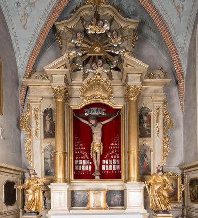 Zdjęcie nr 1: Nastawa architektoniczna, trójosiowa, jednokondygnacyjna ze zwieńczeniem, ustawiona na dwustrefowym cokole, z wyodrębnionymi dwoma prostopadłościanami. Ołtarz prostopadłościenny, z drewnianą mensą. Antepedium ujęte profilowaną ramą z monogramem IHS w polu. 
Osie nastawy wydzielone dwiema parami pilastrów oraz stojącymi przed środkową parą dwiema kolumnami ustawionymi na wydzielonych cokołach. Podpory podtrzymują wyłamujące się ponad nimi belkowanie z mocno wysuniętym gzymsem oraz fragmenty przerwanego przyczółka. Niemal całe pole środkowe wypełnia wnęka w formie stojącego prostokąta zamkniętego łukiem odcinkowym nadwieszonym, ujęta profilowaną ramą, z figurą Chrystusa Ukrzyżowanego. Nad nią rokokowy kartusz z monogramem IHS w polu. Pod nią, w partii predelli, scena z przypowieści o siewcy oraz Umywanie nóg. Na osiach bocznych po dwie arkady w dwóch rzędach ze scenami z życia św. Małgorzaty. Kondygnacja ujęta uszami utworzonymi z rocaille'u. Zwieńczenie w formie kwadratu, flankowane pilastrami przechodzącymi w woluty spływające na belkowanie, zamknięte dwoma odcinkami falowanego gzymsu, zamkniętego szczytem z rocaille'u. W polu, na tle prześwitu oko Opatrzności w otoku z obłoków i uskrzydlonych główek anielskich na tle glorii promienistej. Ołtarz flankowany wysokimi, wolno stojącymi postumentami z figurami św. Piotra i św. Pawła. Struktura polichromowana w odcieniach beżu. W partiach pól antepedium, cokołów, trzonów pilastrów i fryzu retabulum marmoryzacja w odcieniach beżu i brązu; kolumny, profile i ornamentyka złocone, detale srebrzone.  Z tyłu ołtarza tabliczka z napisem: „odnowienie kościoła r(oku) 1882 / z(acnie) w(ielmożnego) x(iędza) proboszcza i. Przybysia / w(ielmożnego) p(ana) Klaeskiego oraz szanownych […] i […] wykonawca tego malowania kościoła Jan Dutkiewicz / wraz czeladzią, Karol Jachimowicz i / Karol Dutkiewicz”.