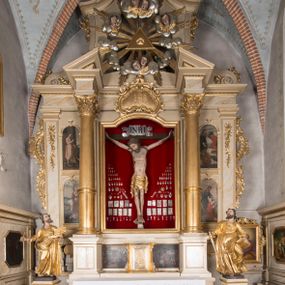 Zdjęcie nr 1: Nastawa architektoniczna, trójosiowa, jednokondygnacyjna ze zwieńczeniem, ustawiona na dwustrefowym cokole, z wyodrębnionymi dwoma prostopadłościanami. Ołtarz prostopadłościenny, z drewnianą mensą. Antepedium ujęte profilowaną ramą z monogramem IHS w polu. 
Osie nastawy wydzielone dwiema parami pilastrów oraz stojącymi przed środkową parą dwiema kolumnami ustawionymi na wydzielonych cokołach. Podpory podtrzymują wyłamujące się ponad nimi belkowanie z mocno wysuniętym gzymsem oraz fragmenty przerwanego przyczółka. Niemal całe pole środkowe wypełnia wnęka w formie stojącego prostokąta zamkniętego łukiem odcinkowym nadwieszonym, ujęta profilowaną ramą, z figurą Chrystusa Ukrzyżowanego. Nad nią rokokowy kartusz z monogramem IHS w polu. Pod nią, w partii predelli, scena z przypowieści o siewcy oraz Umywanie nóg. Na osiach bocznych po dwie arkady w dwóch rzędach ze scenami z życia św. Małgorzaty. Kondygnacja ujęta uszami utworzonymi z rocaille'u. Zwieńczenie w formie kwadratu, flankowane pilastrami przechodzącymi w woluty spływające na belkowanie, zamknięte dwoma odcinkami falowanego gzymsu, zamkniętego szczytem z rocaille'u. W polu, na tle prześwitu oko Opatrzności w otoku z obłoków i uskrzydlonych główek anielskich na tle glorii promienistej. Ołtarz flankowany wysokimi, wolno stojącymi postumentami z figurami św. Piotra i św. Pawła. Struktura polichromowana w odcieniach beżu. W partiach pól antepedium, cokołów, trzonów pilastrów i fryzu retabulum marmoryzacja w odcieniach beżu i brązu; kolumny, profile i ornamentyka złocone, detale srebrzone.  Z tyłu ołtarza tabliczka z napisem: „odnowienie kościoła r(oku) 1882 / z(acnie) w(ielmożnego) x(iędza) proboszcza i. Przybysia / w(ielmożnego) p(ana) Klaeskiego oraz szanownych […] i […] wykonawca tego malowania kościoła Jan Dutkiewicz / wraz czeladzią, Karol Jachimowicz i / Karol Dutkiewicz”.