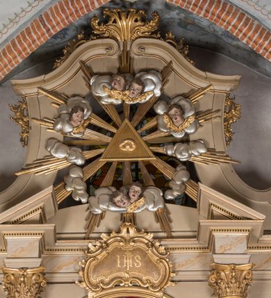 Zdjęcie nr 3: Nastawa architektoniczna, trójosiowa, jednokondygnacyjna ze zwieńczeniem, ustawiona na dwustrefowym cokole, z wyodrębnionymi dwoma prostopadłościanami. Ołtarz prostopadłościenny, z drewnianą mensą. Antepedium ujęte profilowaną ramą z monogramem IHS w polu. 
Osie nastawy wydzielone dwiema parami pilastrów oraz stojącymi przed środkową parą dwiema kolumnami ustawionymi na wydzielonych cokołach. Podpory podtrzymują wyłamujące się ponad nimi belkowanie z mocno wysuniętym gzymsem oraz fragmenty przerwanego przyczółka. Niemal całe pole środkowe wypełnia wnęka w formie stojącego prostokąta zamkniętego łukiem odcinkowym nadwieszonym, ujęta profilowaną ramą, z figurą Chrystusa Ukrzyżowanego. Nad nią rokokowy kartusz z monogramem IHS w polu. Pod nią, w partii predelli, scena z przypowieści o siewcy oraz Umywanie nóg. Na osiach bocznych po dwie arkady w dwóch rzędach ze scenami z życia św. Małgorzaty. Kondygnacja ujęta uszami utworzonymi z rocaille&#039;u. Zwieńczenie w formie kwadratu, flankowane pilastrami przechodzącymi w woluty spływające na belkowanie, zamknięte dwoma odcinkami falowanego gzymsu, zamkniętego szczytem z rocaille&#039;u. W polu, na tle prześwitu oko Opatrzności w otoku z obłoków i uskrzydlonych główek anielskich na tle glorii promienistej. Ołtarz flankowany wysokimi, wolno stojącymi postumentami z figurami św. Piotra i św. Pawła. Struktura polichromowana w odcieniach beżu. W partiach pól antepedium, cokołów, trzonów pilastrów i fryzu retabulum marmoryzacja w odcieniach beżu i brązu; kolumny, profile i ornamentyka złocone, detale srebrzone.  Z tyłu ołtarza tabliczka z napisem: „odnowienie kościoła r(oku) 1882 / z(acnie) w(ielmożnego) x(iędza) proboszcza i. Przybysia / w(ielmożnego) p(ana) Klaeskiego oraz szanownych […] i […] wykonawca tego malowania kościoła Jan Dutkiewicz / wraz czeladzią, Karol Jachimowicz i / Karol Dutkiewicz”.