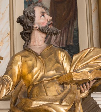 Zdjęcie nr 19: Nastawa architektoniczna, trójosiowa, jednokondygnacyjna ze zwieńczeniem, ustawiona na dwustrefowym cokole, z wyodrębnionymi dwoma prostopadłościanami. Ołtarz prostopadłościenny, z drewnianą mensą. Antepedium ujęte profilowaną ramą z monogramem IHS w polu. 
Osie nastawy wydzielone dwiema parami pilastrów oraz stojącymi przed środkową parą dwiema kolumnami ustawionymi na wydzielonych cokołach. Podpory podtrzymują wyłamujące się ponad nimi belkowanie z mocno wysuniętym gzymsem oraz fragmenty przerwanego przyczółka. Niemal całe pole środkowe wypełnia wnęka w formie stojącego prostokąta zamkniętego łukiem odcinkowym nadwieszonym, ujęta profilowaną ramą, z figurą Chrystusa Ukrzyżowanego. Nad nią rokokowy kartusz z monogramem IHS w polu. Pod nią, w partii predelli, scena z przypowieści o siewcy oraz Umywanie nóg. Na osiach bocznych po dwie arkady w dwóch rzędach ze scenami z życia św. Małgorzaty. Kondygnacja ujęta uszami utworzonymi z rocaille'u. Zwieńczenie w formie kwadratu, flankowane pilastrami przechodzącymi w woluty spływające na belkowanie, zamknięte dwoma odcinkami falowanego gzymsu, zamkniętego szczytem z rocaille'u. W polu, na tle prześwitu oko Opatrzności w otoku z obłoków i uskrzydlonych główek anielskich na tle glorii promienistej. Ołtarz flankowany wysokimi, wolno stojącymi postumentami z figurami św. Piotra i św. Pawła. Struktura polichromowana w odcieniach beżu. W partiach pól antepedium, cokołów, trzonów pilastrów i fryzu retabulum marmoryzacja w odcieniach beżu i brązu; kolumny, profile i ornamentyka złocone, detale srebrzone.  Z tyłu ołtarza tabliczka z napisem: „odnowienie kościoła r(oku) 1882 / z(acnie) w(ielmożnego) x(iędza) proboszcza i. Przybysia / w(ielmożnego) p(ana) Klaeskiego oraz szanownych […] i […] wykonawca tego malowania kościoła Jan Dutkiewicz / wraz czeladzią, Karol Jachimowicz i / Karol Dutkiewicz”.