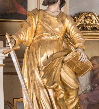 Zdjęcie nr 24: Nastawa architektoniczna, trójosiowa, jednokondygnacyjna ze zwieńczeniem, ustawiona na dwustrefowym cokole, z wyodrębnionymi dwoma prostopadłościanami. Ołtarz prostopadłościenny, z drewnianą mensą. Antepedium ujęte profilowaną ramą z monogramem IHS w polu. 
Osie nastawy wydzielone dwiema parami pilastrów oraz stojącymi przed środkową parą dwiema kolumnami ustawionymi na wydzielonych cokołach. Podpory podtrzymują wyłamujące się ponad nimi belkowanie z mocno wysuniętym gzymsem oraz fragmenty przerwanego przyczółka. Niemal całe pole środkowe wypełnia wnęka w formie stojącego prostokąta zamkniętego łukiem odcinkowym nadwieszonym, ujęta profilowaną ramą, z figurą Chrystusa Ukrzyżowanego. Nad nią rokokowy kartusz z monogramem IHS w polu. Pod nią, w partii predelli, scena z przypowieści o siewcy oraz Umywanie nóg. Na osiach bocznych po dwie arkady w dwóch rzędach ze scenami z życia św. Małgorzaty. Kondygnacja ujęta uszami utworzonymi z rocaille'u. Zwieńczenie w formie kwadratu, flankowane pilastrami przechodzącymi w woluty spływające na belkowanie, zamknięte dwoma odcinkami falowanego gzymsu, zamkniętego szczytem z rocaille'u. W polu, na tle prześwitu oko Opatrzności w otoku z obłoków i uskrzydlonych główek anielskich na tle glorii promienistej. Ołtarz flankowany wysokimi, wolno stojącymi postumentami z figurami św. Piotra i św. Pawła. Struktura polichromowana w odcieniach beżu. W partiach pól antepedium, cokołów, trzonów pilastrów i fryzu retabulum marmoryzacja w odcieniach beżu i brązu; kolumny, profile i ornamentyka złocone, detale srebrzone.  Z tyłu ołtarza tabliczka z napisem: „odnowienie kościoła r(oku) 1882 / z(acnie) w(ielmożnego) x(iędza) proboszcza i. Przybysia / w(ielmożnego) p(ana) Klaeskiego oraz szanownych […] i […] wykonawca tego malowania kościoła Jan Dutkiewicz / wraz czeladzią, Karol Jachimowicz i / Karol Dutkiewicz”.