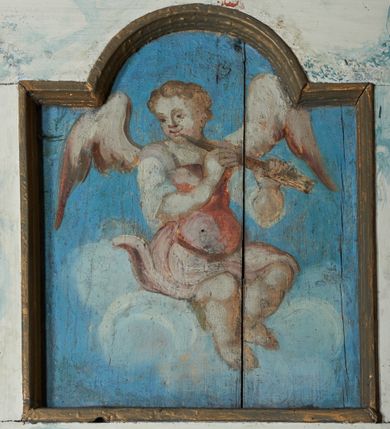 Zdjęcie nr 5: Balustrada chóru muzycznego dziewięcioosiowa, jednokondygnacyjna, od spodu z podwieszonym lambrekinem, na osi środkowej wypukła. Osie flankowane kolumienkami ustawionymi na cokołach, które podtrzymują imposty ustawione pod kątem, wyłamujące profilowany gzyms balustrady. Trzony kolumienek malowane na czarno, kapitele stylizowane na korynckie, złocone. W każdej osi umieszczona płycina w kształcie stojącego prostokąta zamknięta łukiem nadwieszonym. Kolejno od lewej strony malowane w płycinach obrazy: aniołek grający na trąbce, aniołek grający na bębnach, ponownie aniołek grający na trąbce i aniołek grający na skrzypach. Na środku osi płycina w kształcie stojącego prostokąta zamknięta trójkątnie o wyłamanym zwieńczeniu, w polu przedstawienie króla Dawida grającego na harfie. U góry banderola z napisem „LAUDATE DOMINUM IN CITHARA”. Po drugiej stronie balustrady, kolejno od lewej: aniołek grający na wiolonczeli, aniołek grający na trąbce, aniołek grający na flecie i aniołek grający na mandolinie. Wszystkie postacie ukazane na jasnobłękitnym tle, na chmurze białych obłoków. Anioły półnagie, ubrane w czerwone szaty. Struktura balustrady marmoryzowana na biało z niebieskimi przetarciami, detale złocone i malowane na czarno.
