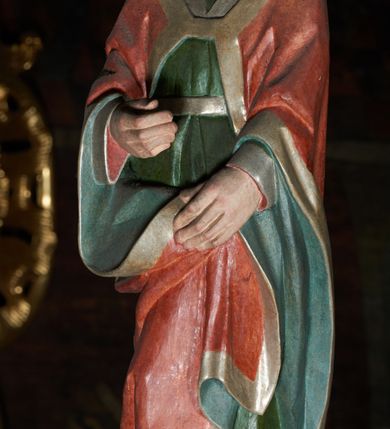 Zdjęcie nr 7: Łuk tęczowy o półkolistym wykroju wsparty na kroksztynach. Belka profilowana, współczesna (z czasów ostatniej konserwacji, nawiązująca do poprzedniej gotyckiej). W centrum krucyfiks z postacią Chrystusa umarłego, po prawej św. Jan Ewangelista, po lewej Matka Boska i św. Maria Magdalena. Chrystus przybity do krzyża trzema gwoździami, sylwetka w delikatnym zwisie, z głową przechyloną na prawe ramię, o silnie podkreślonej anatomii ciała, z zaznaczonymi śladami męki. Perizonium w formie tkaniny przewiązanej na prawym biodrze. Twarz podłużna, okolona zarostem; włosy długie spływające na prawe ramię w kręcone pukle, na głowie korona cierniowa. Po prawej stronie rzeźba św. Jana Ewangelisty, ukazanego w postawie stojącej, zwróconego w trzech czwartych w prawo, lewą ręką przytrzymującego z przodu płaszcz. Święty jest ubrany w długą, zieloną suknię z długimi rękawami oraz czerwony płaszcz, spięty na piersi, zdobiony na brzegach grubą lamelką. Twarz owalna, policzki silnie zarumienione, małe usta, długi i wąski nos, wzrok skierowany przed siebie, zmarszczone brwi. Włosy jasne, spływające do ramion ciasno ułożonymi puklami. Po lewej stronie krucyfiksu rzeźba św. Marii Magdaleny ukazana w pozycji klęczącej, z prawego profilu, z wyciągniętymi w stronę krzyża dłońmi. Święta jest ubrana w długą, czerwoną suknię oraz obszerny zielony płaszcz ze srebrną podszewką, na głowie ma biały welon. Twarz owalna, z wyraźnie zaznaczonym podbródkiem, zmarszczone brwi; spod welonu spływają na lewe ramię długie i jasne włosy. Za nią rzeźba Matki Boskiej ustawiona w kontrapoście, z prawą nogą ugiętą w kolanie, ze skrzyżowanymi na piersi rękami. Maria jest ubrana w długą, bordową suknię oraz błękitny płaszcz z czerwoną podszewką. Twarz szeroka, z wyraźnie zaznaczonym podbródkiem, wzrok skierowany w dal, zmarszczone brwi. Rzeźby ustawione na półkolistych, zielonych cokolikach. Polichromia w odsłoniętych partiach ciała naturalistyczna, detale złocone. 
